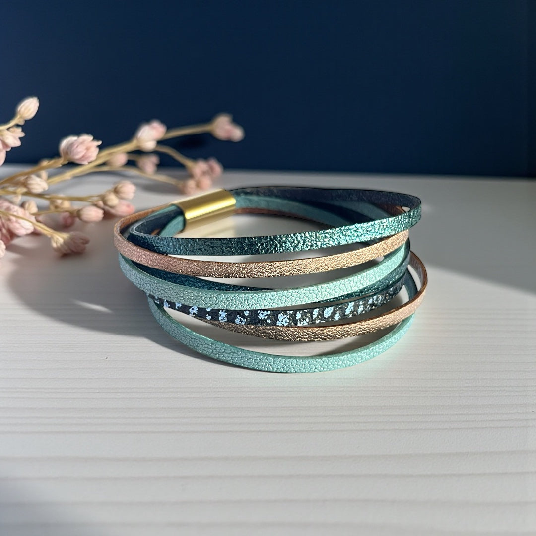 Bracelet en cuir , liens multiples dans les tons bleus et rose, sur fond beige et bleu