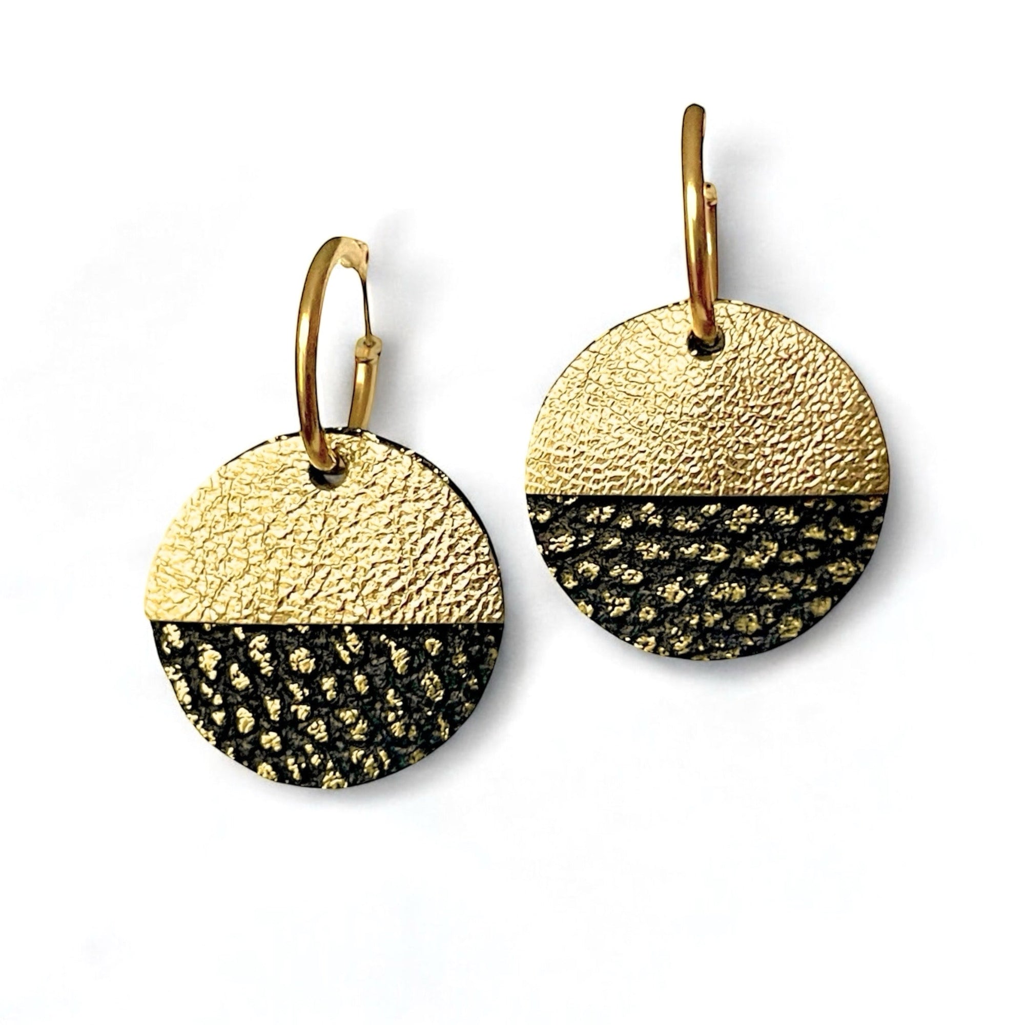 Boucles créoles dorées avec pendentifs en forme de disques et demi-lunes en cuirs noirs grainé or et doré antique, sur fond blanc