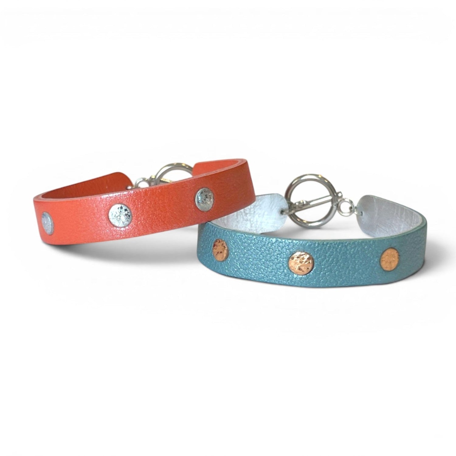 2 Bracelets argentés empilés en cuirs bicolore corail nacré et argent brillant froissé, et bleu gris nacré et or rosé froissé, empilés les uns sur les autres, sur fond blanc