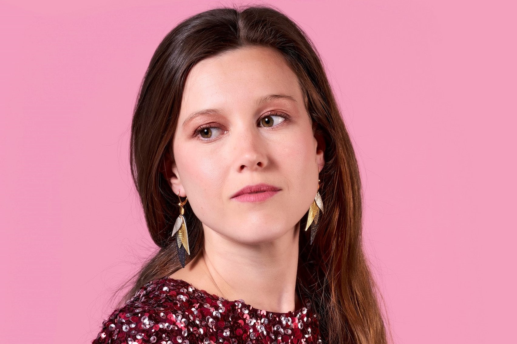 Jeune femme portant les boucles d'oreilles Ara en plumes de cuir de la marque Nune