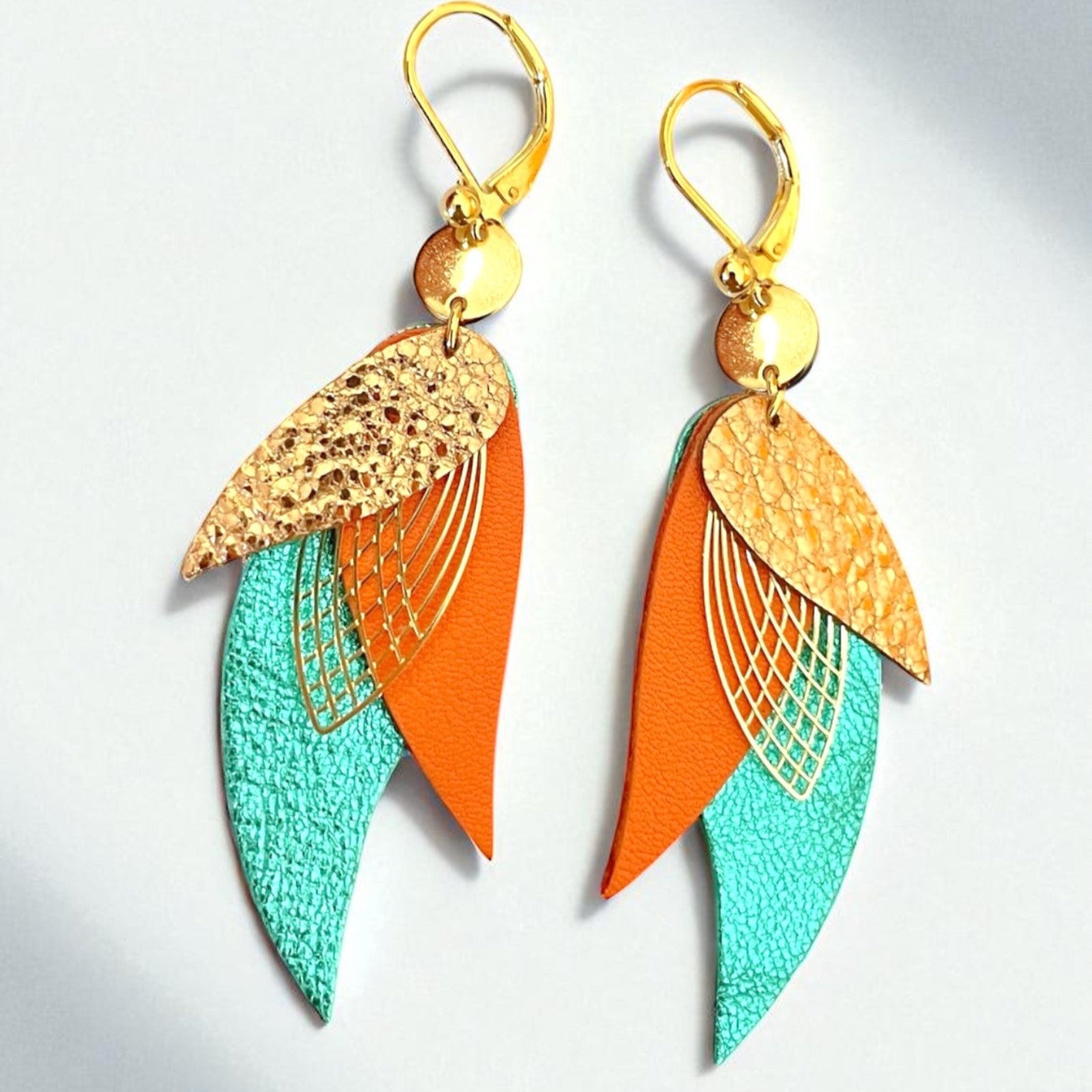 boucles d'oreilles dorées Nune modèle Ara en plumes de cuirs or rosé froissé, orange et turquoise métallisé, sur fond blanc