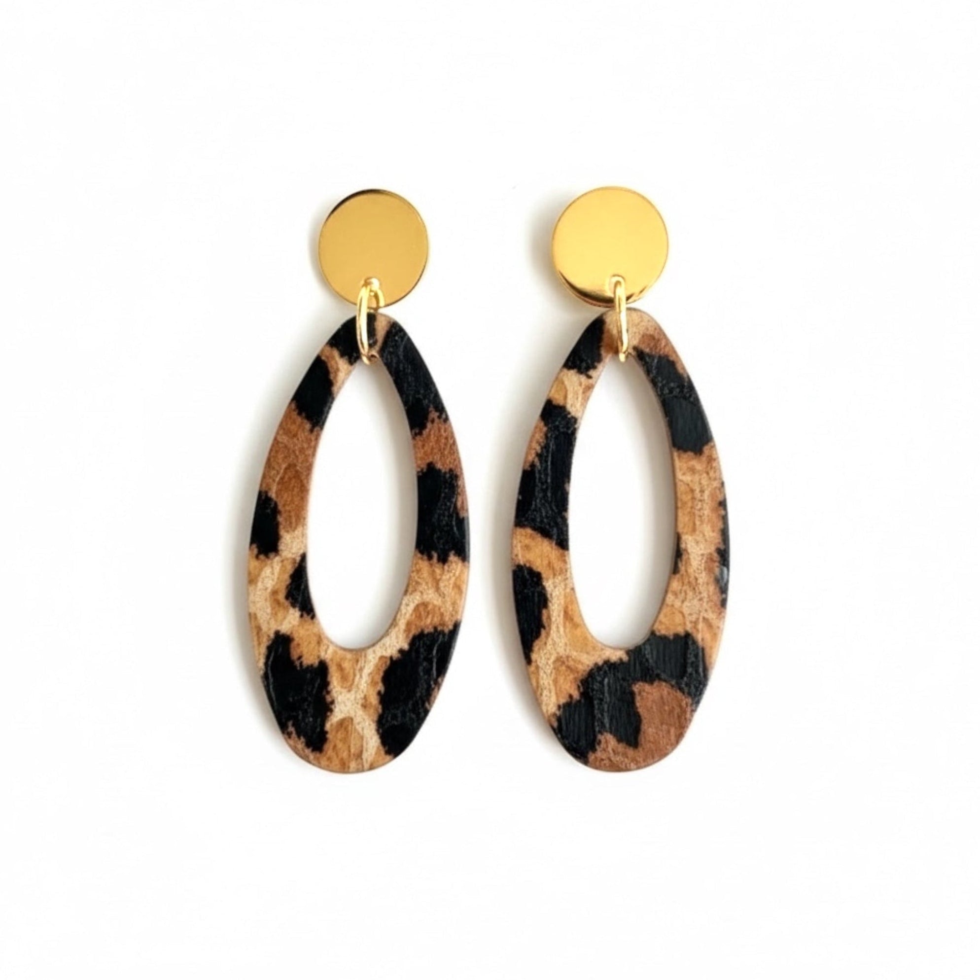 Puces d'oreilles dorées Drys de la marque Nune, avec leurs anneaux ovales en cuir léopard, sur fond blanc