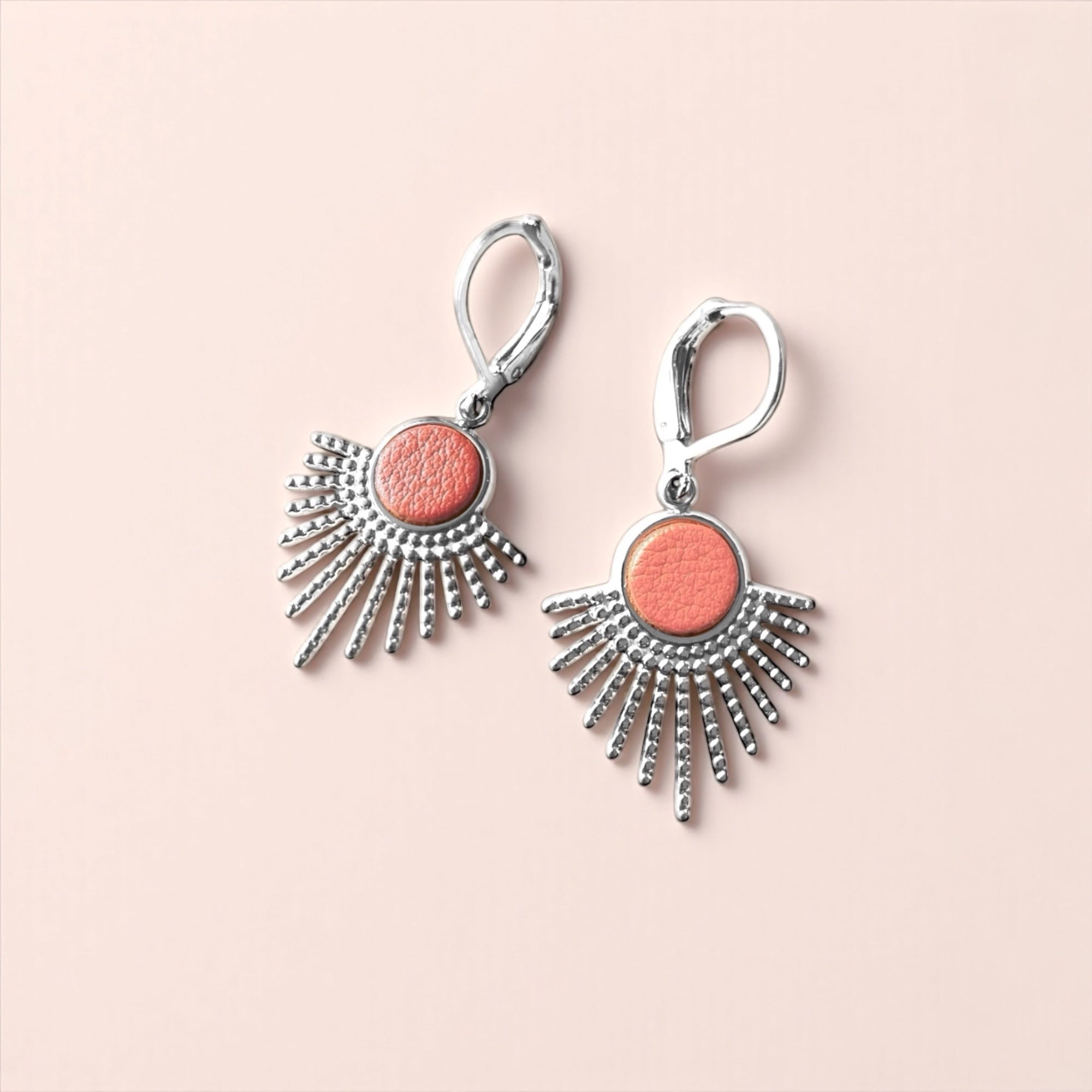 Petites boucles d'oreilles argentées Miria forme soleils avec cabochons de cuir corail nacré sur fond rose clair