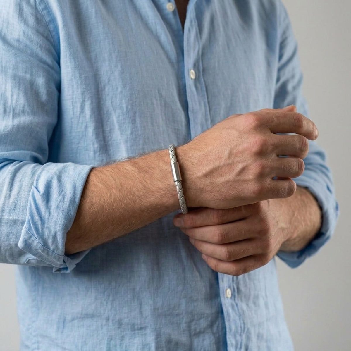 Bracelet homme en cuir tressé argent avec fermoir cylindrique aimanté en acier inoxydable, porté au poignet