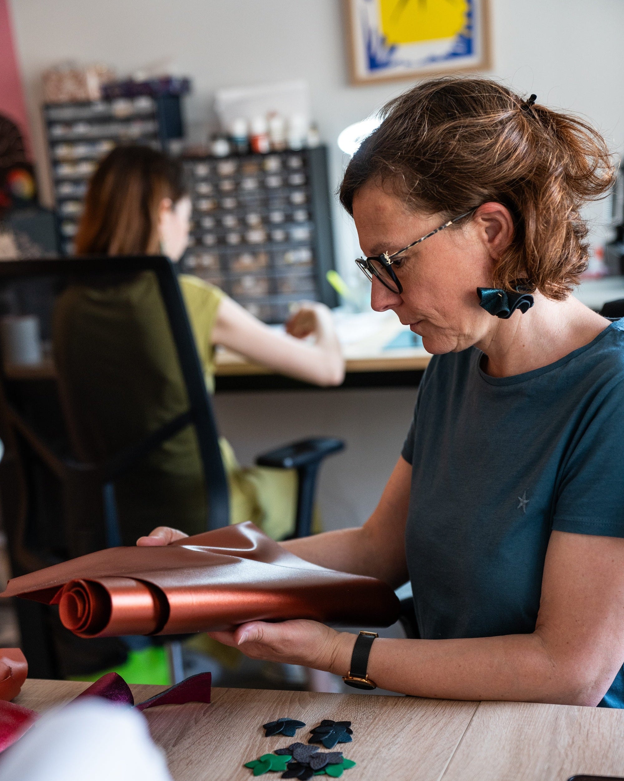 Céline et Amélie au travail dans l'atelier Nune. Céline sélectionne des cuirs pour un nouveau modèle, et Amélie est en pleine fabrication de bijoux.