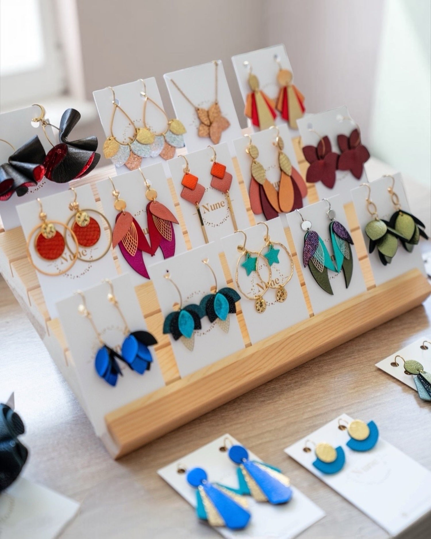 Présentoir en bois garni de boucles d'oreilles et colliers Nune en cuirs de toutes les couleurs.