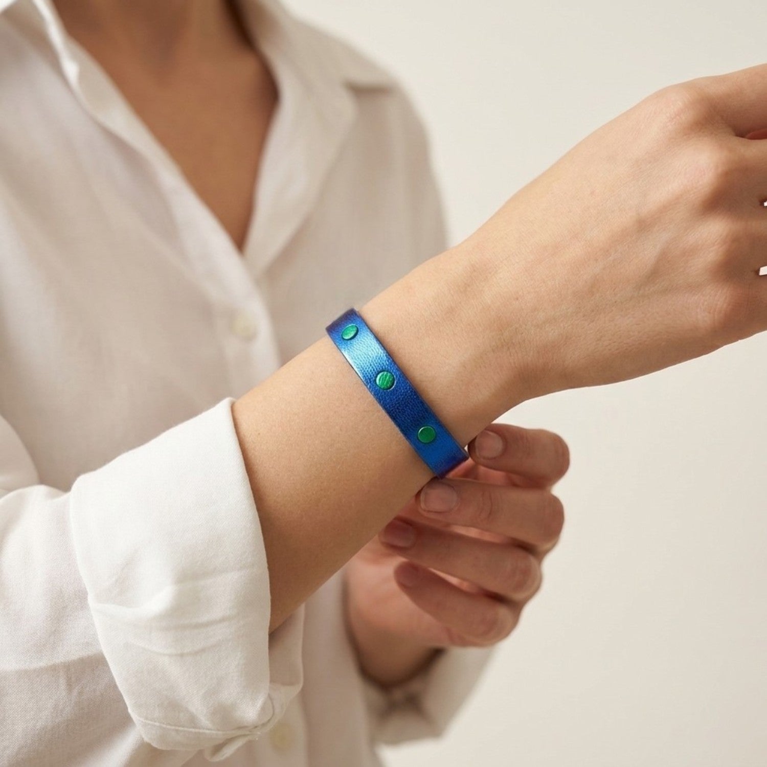 Bracelet argenté en cuirs bicolores bleu cobalt métallisé et vert métallisé, porté au poignet