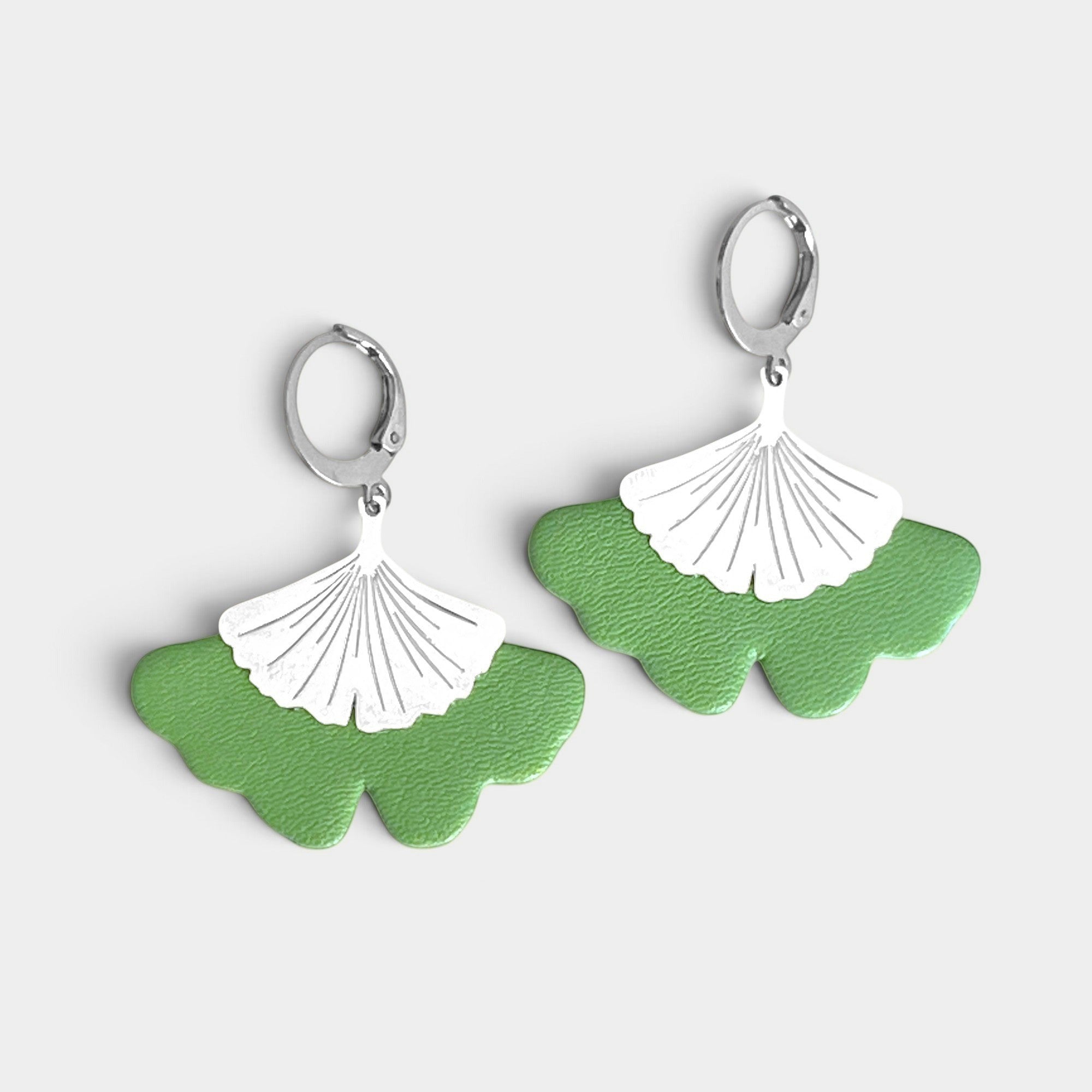 Boucles d'oreilles argentées pendantes en cuir vert pomme pastel en forme de gingko, sur fond gris clair