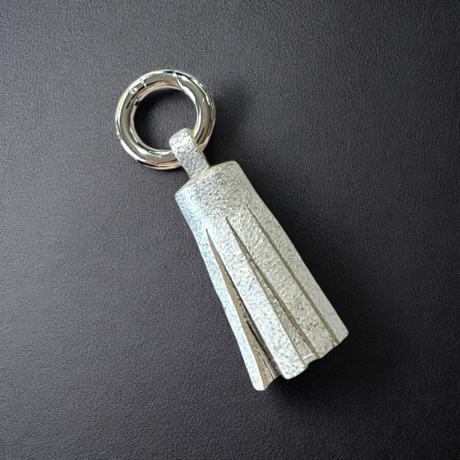 porte-clé argent en cuir blanc nacré argent , en forme de pompon, sur fond noir
