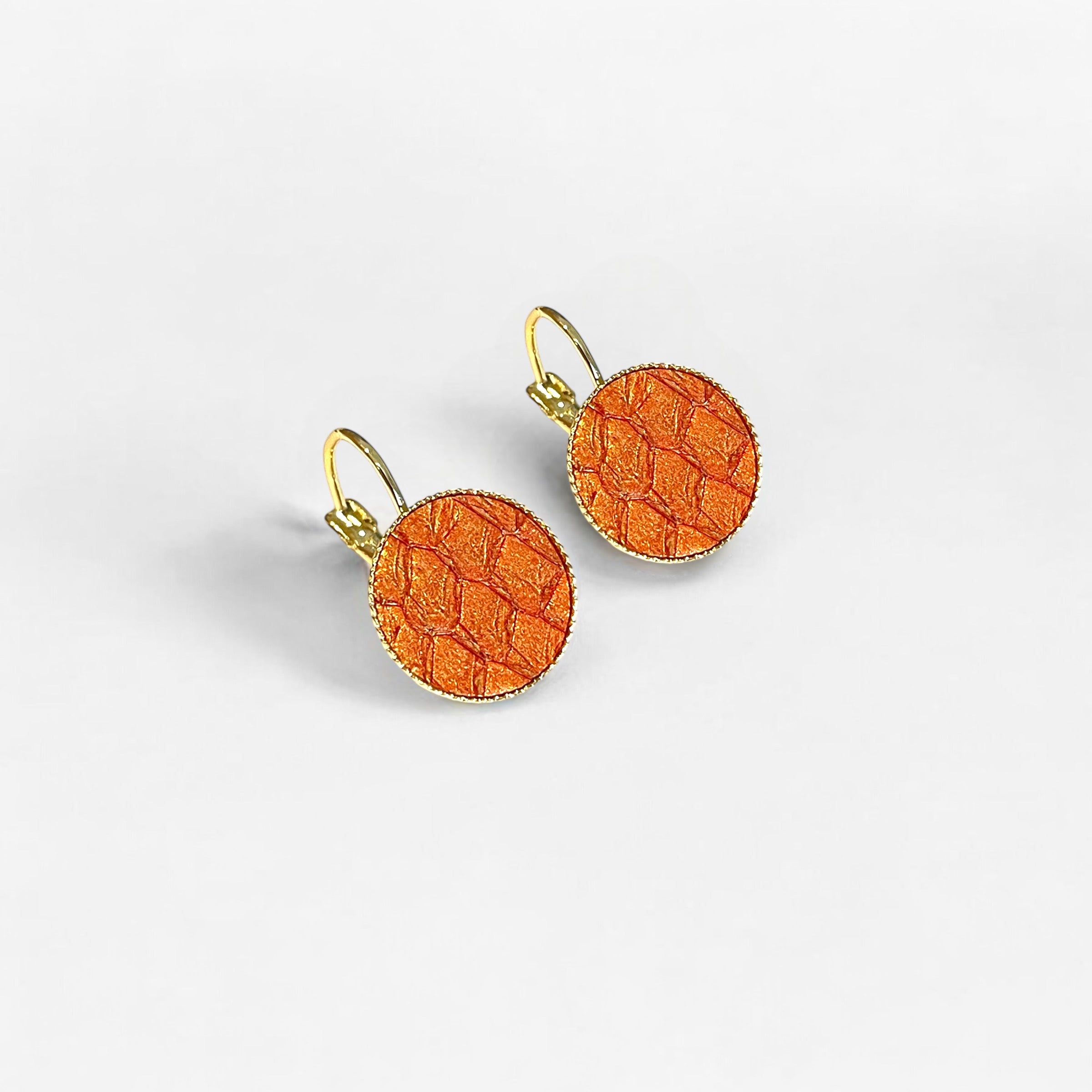 Petites boucles d'oreilles dormeuses dorées serties de fin cuir marin orangé or, sur fond blanc