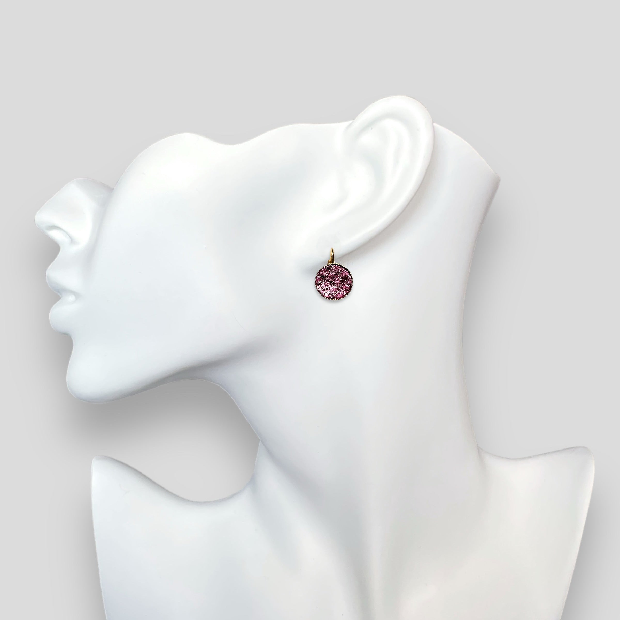 Petites boucles d'oreilles dormeuses dorées serties de fin cuir marin grenat métallisé, portées à l'oreille sur un buste blanc