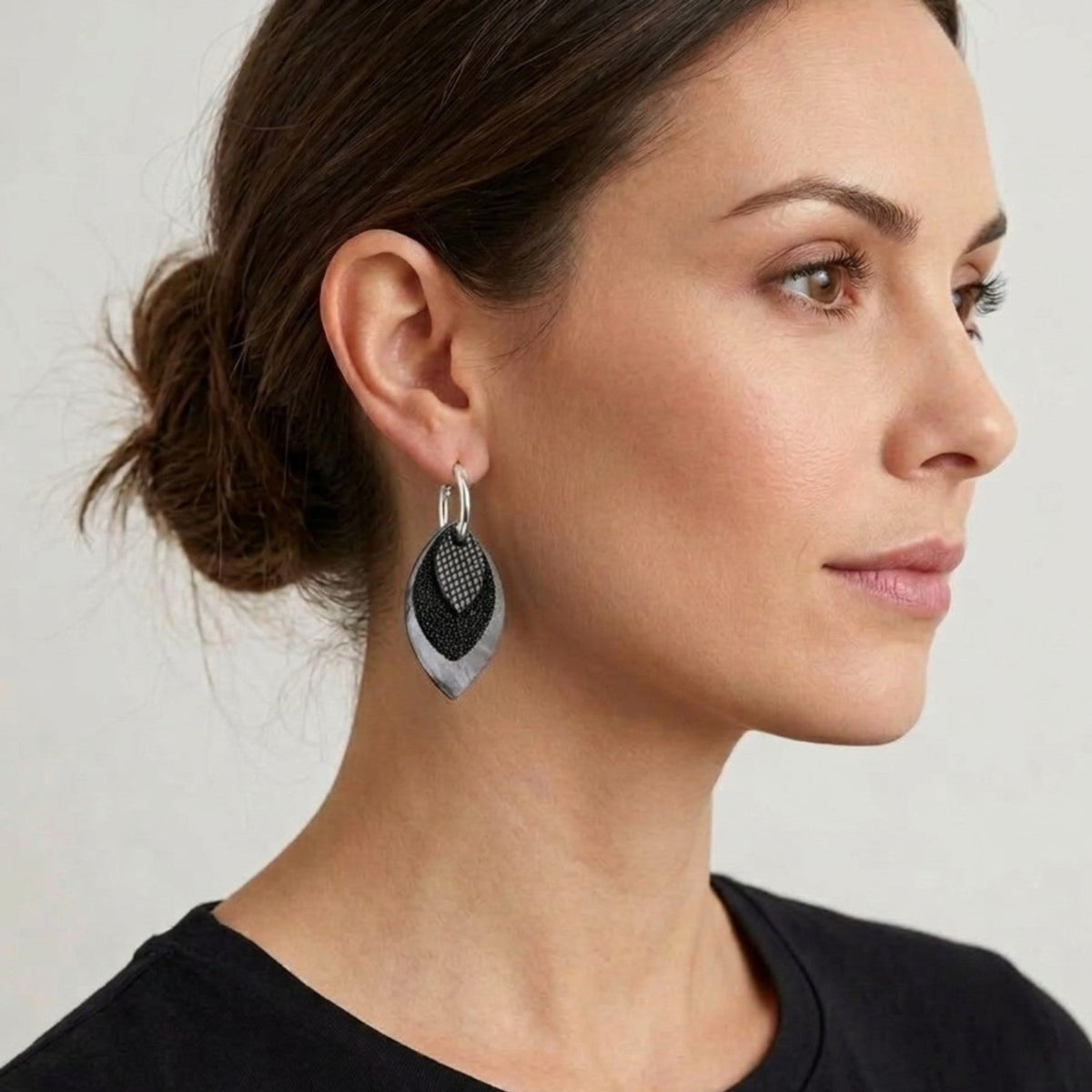 Créoles argentées avec pendentifs modulables en forme de feuilles en cuirs noir petit grain irisé, noir grainé pailleté et léopard noir vernis, portées