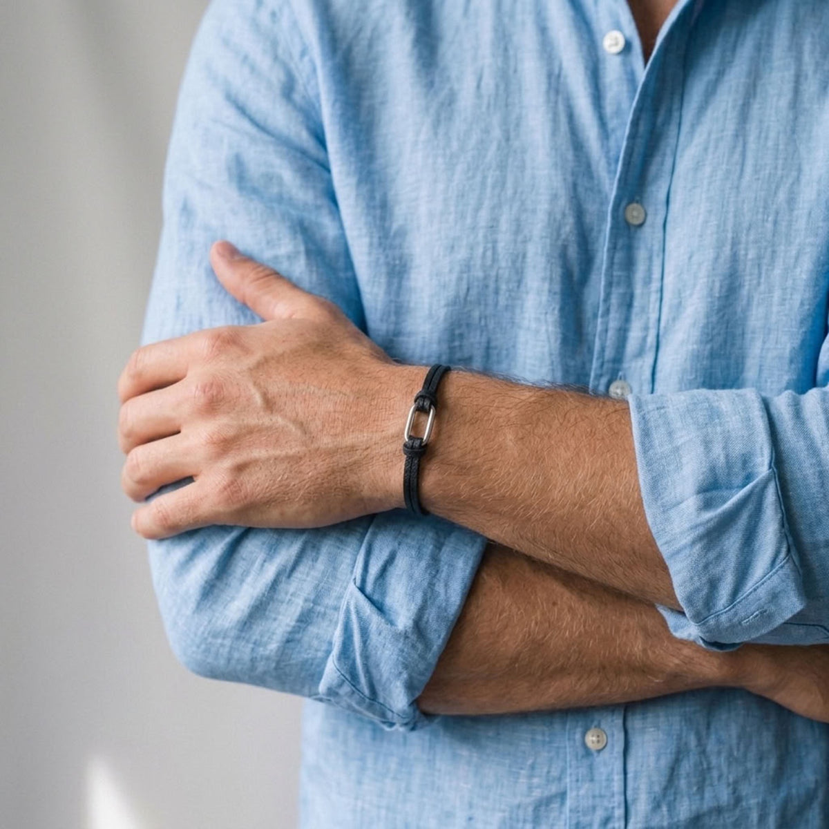 Bracelet homme à boucle argentée en fins liens de cuir noir avec fermoir aimanté argenté, porté au poignet
