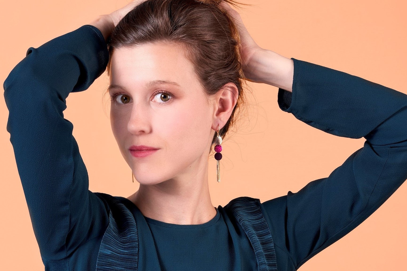 Jeune femme portant les boucles d'oreilles Janis dorées avec pastilles de cuir de la marque Nune