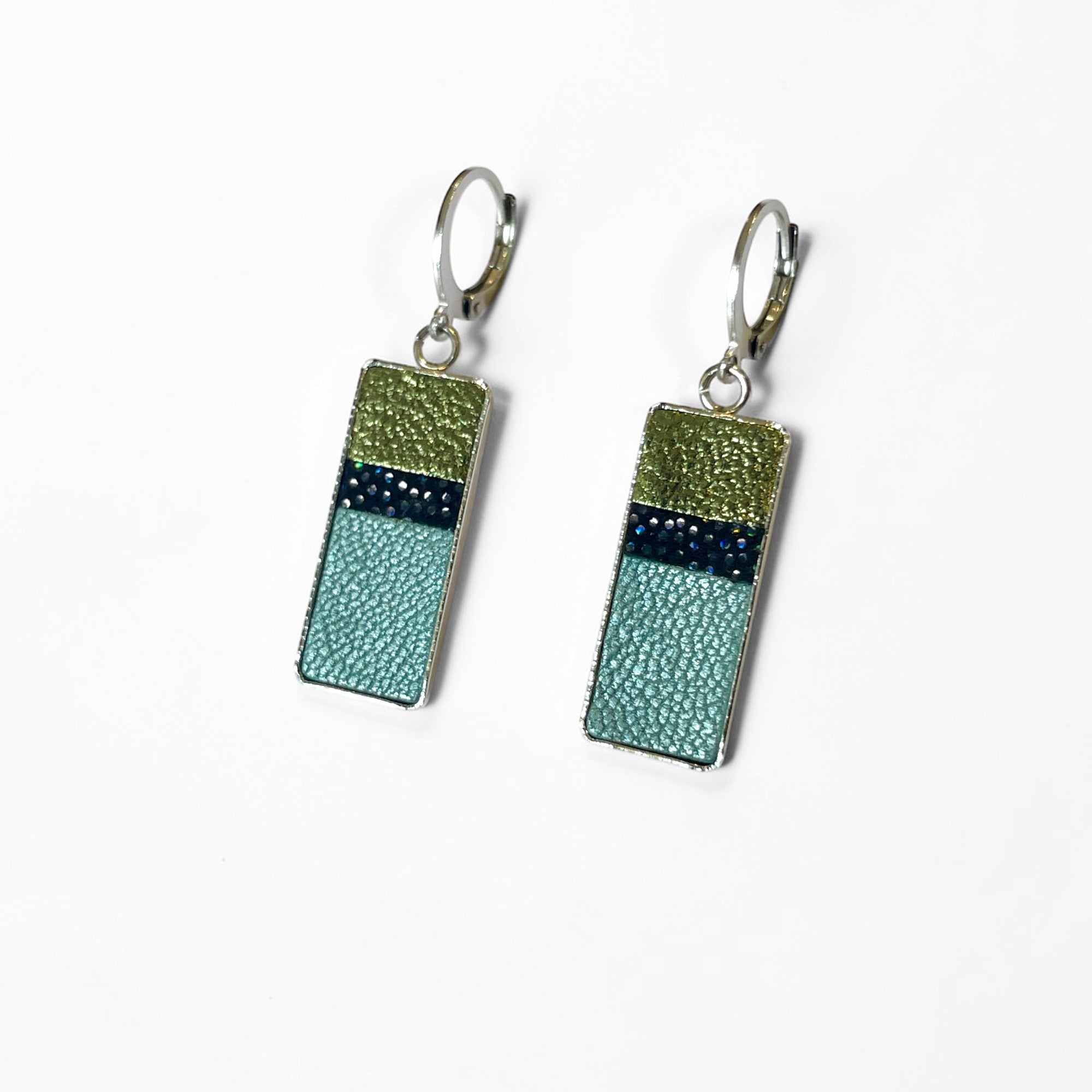 Petites boucles d'oreilles argentées pendantes rectangulaires verticales tricolores en cuirs kaki métallisé, noir à pois holographiques et bleu gris nacré, posées à plat sur fond blanc