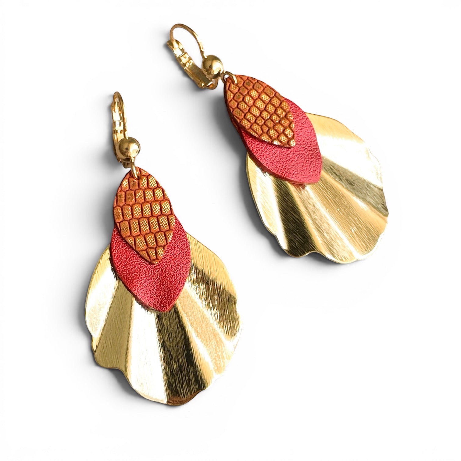 Boucles d'oreilles dorées en forme de coquillages avec pétales de cuir rouge orangé nacré et orangé or façon serpent, sur fond cuir blanc