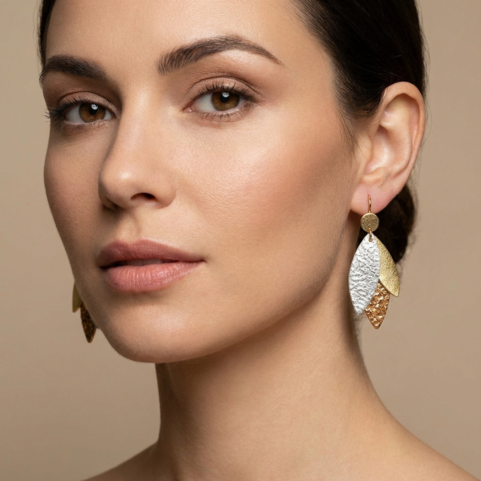 Boucle d'oreille dorée Nune modèle Ombline en cuirs 3 Ors portée aux oreilles par une femme brune