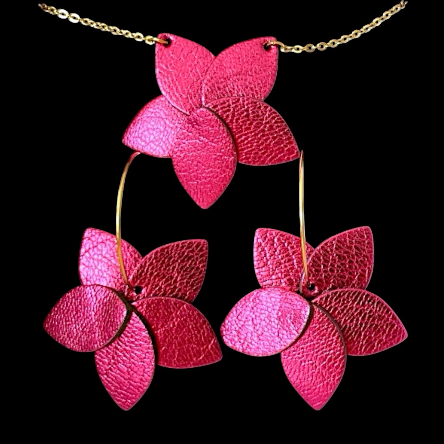 Parure collier doré et Petites boucles d'oreilles en forme de fleurs en cuir fushia métallisé , montées sur créoles dorées, sur fond noir