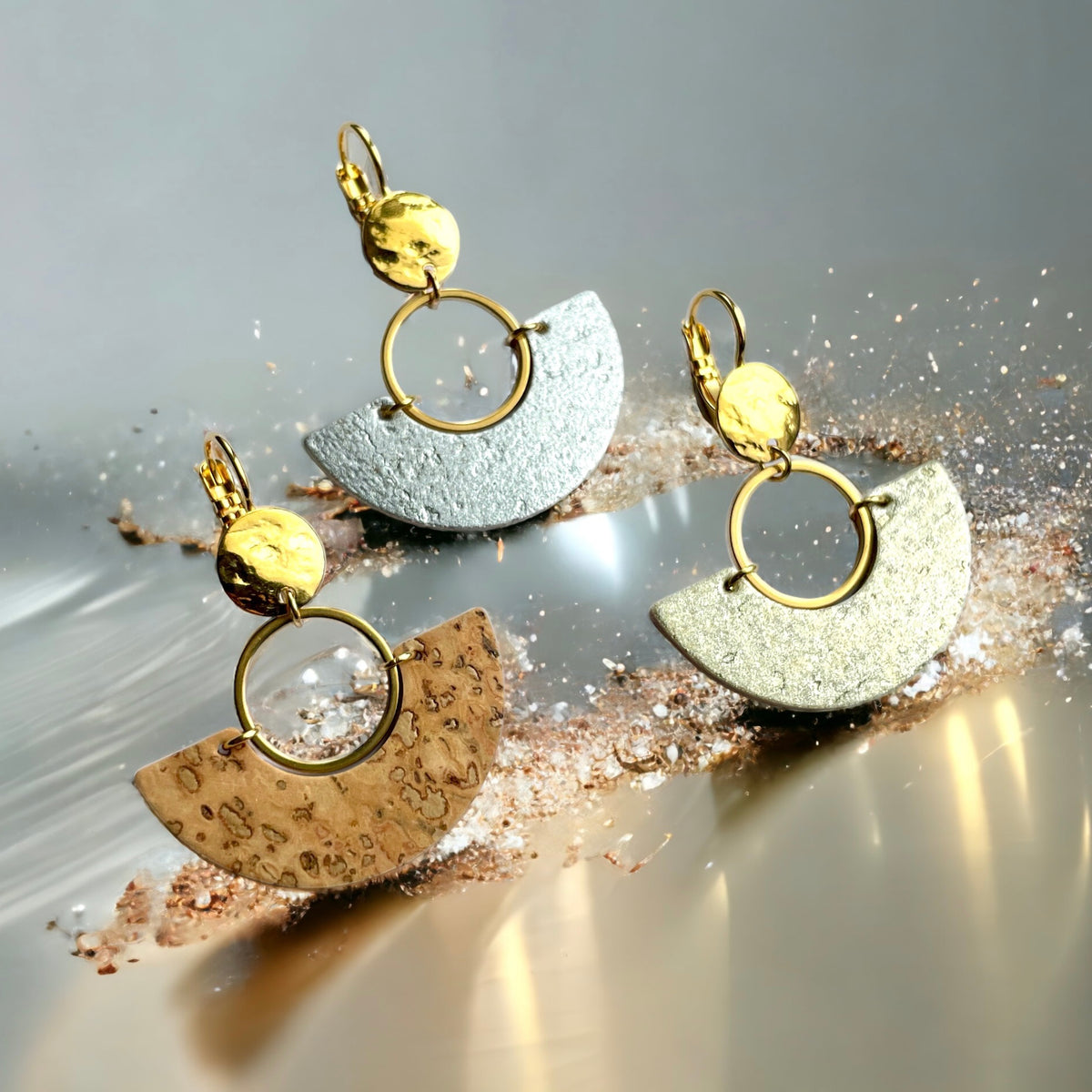 Les boucles d'oreilles Artea, graphiques et élégantes en forme de demi-lunes, sont fabriquées à la main avec de fines pièces de liège brut, doré ou argenté