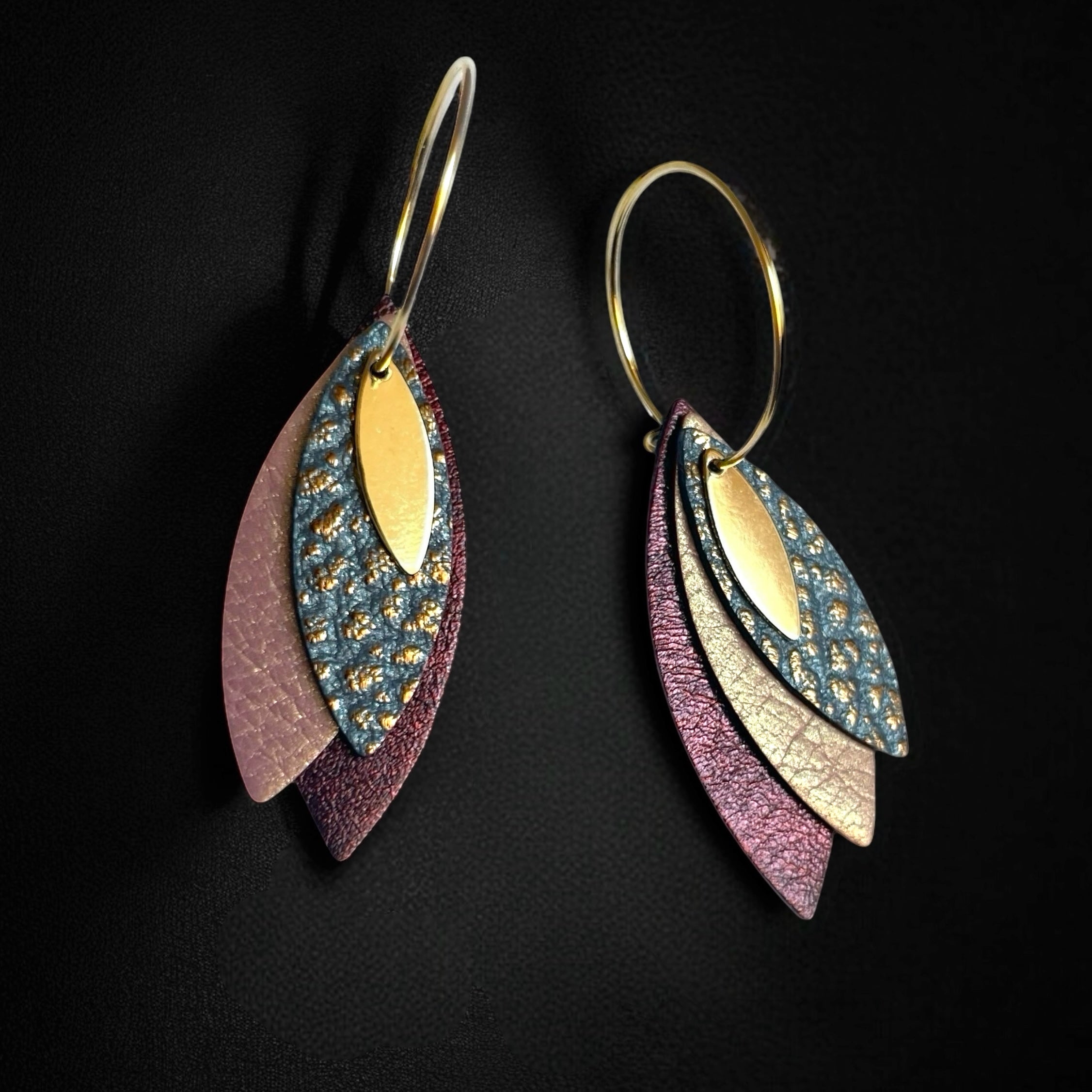 Boucles d'oreilles créoles dorées Nune modèle Piume en cuirs gris mordoré grainé, vieux rose nacré et grenat métallisé, sur fond bleu nuit