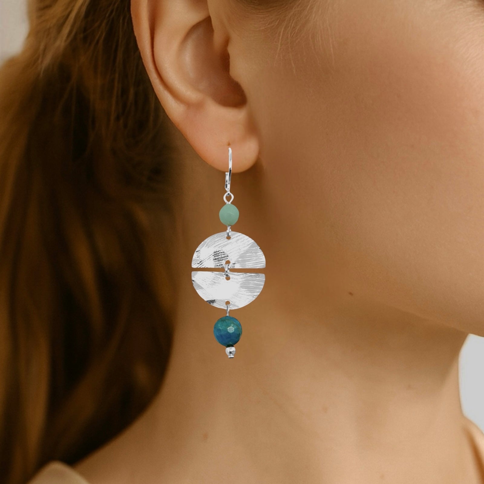 Boucles d'oreilles pendantes de forme ronde avec 2 demi-lunes, en métal martelé argenté et perles d'amazonite et d'apatite bleue, portées à l'oreille