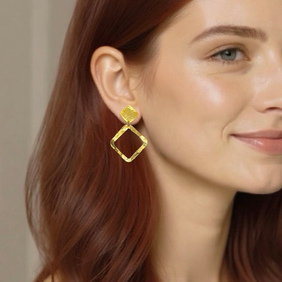 Boucles d'oreilles puces dorées à l'or fin en métal martelé avec pendentif en forme de losange, portées aux oreilles