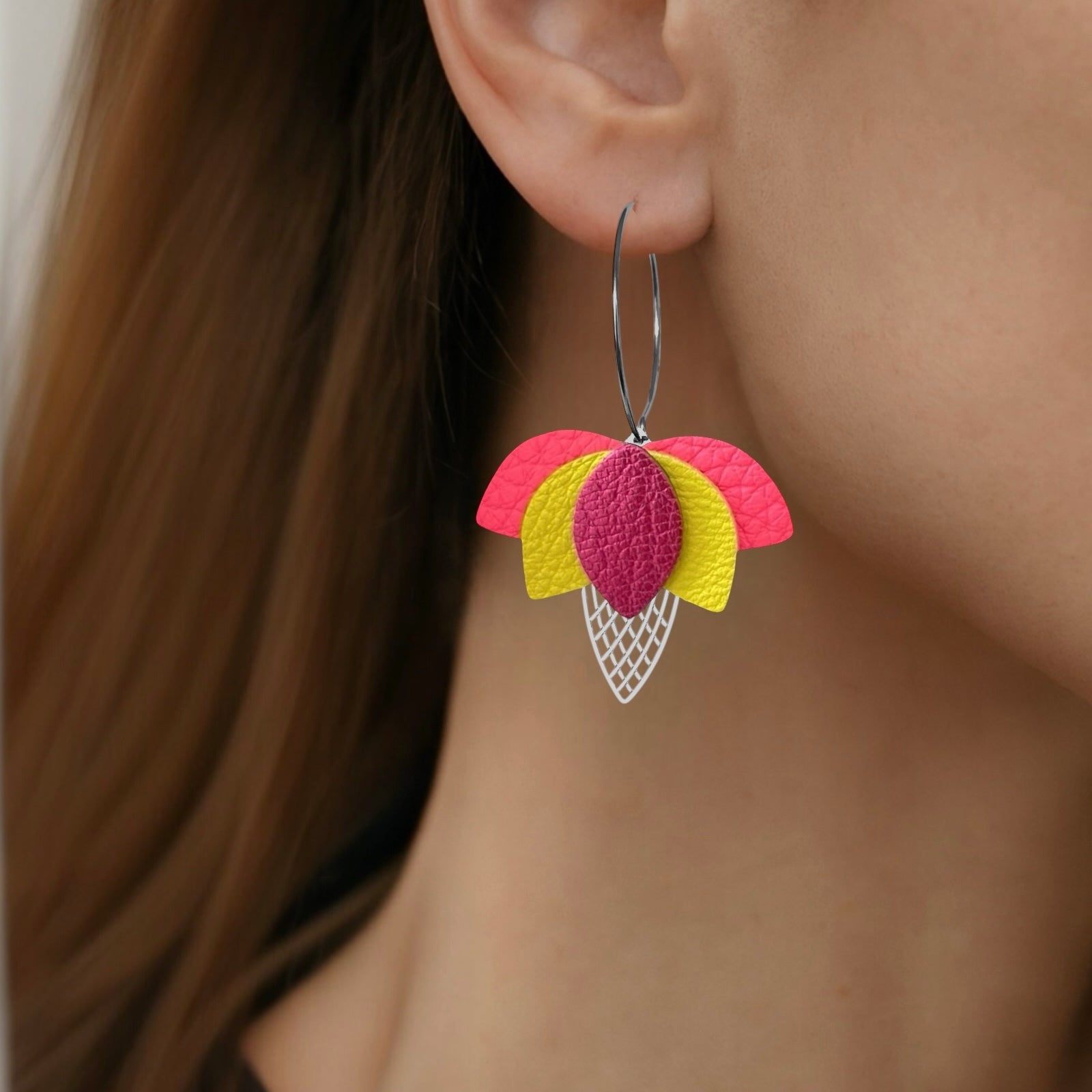 Créoles argentées en forme de fleurs de Lotus en cuirs rose fluo grainé, jaune citron et fushia métallisé, portées aux oreilles