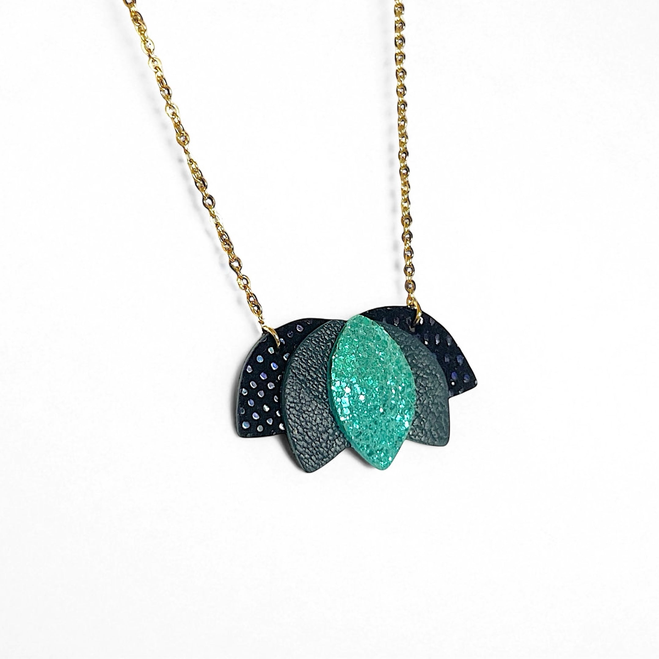 Collier dorée en forme de fleur de Lotus en cuirs noir grainé irisé, vert sombre et vert émeraude brillant intense sur fond blanc