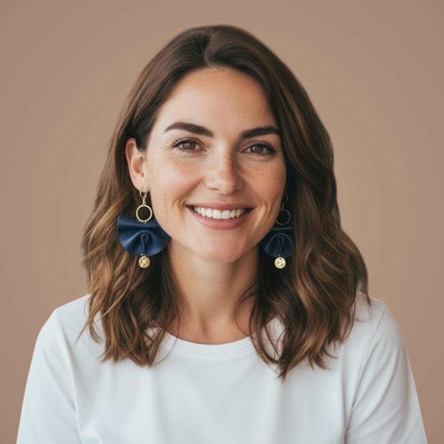 Grandes boucles d'oreilles dorées en éventails de cuir plissé recyclé bleu marine satiné, portées aux oreilles