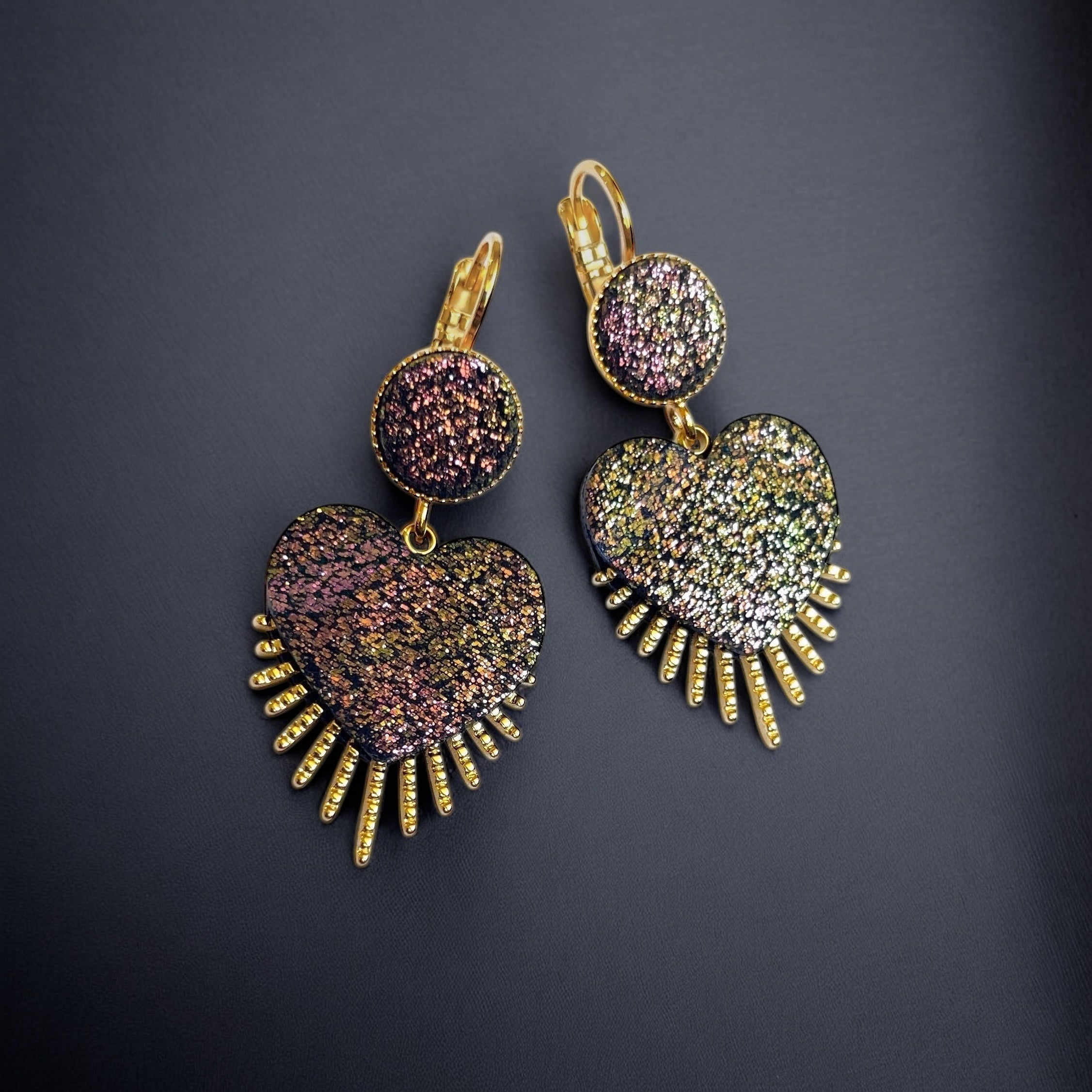 NUNE Boucles d'oreilles dorées en forme de cœurs style ex-voto en cuir pailleté recyclé noir pailleté irisé, sur fond noir