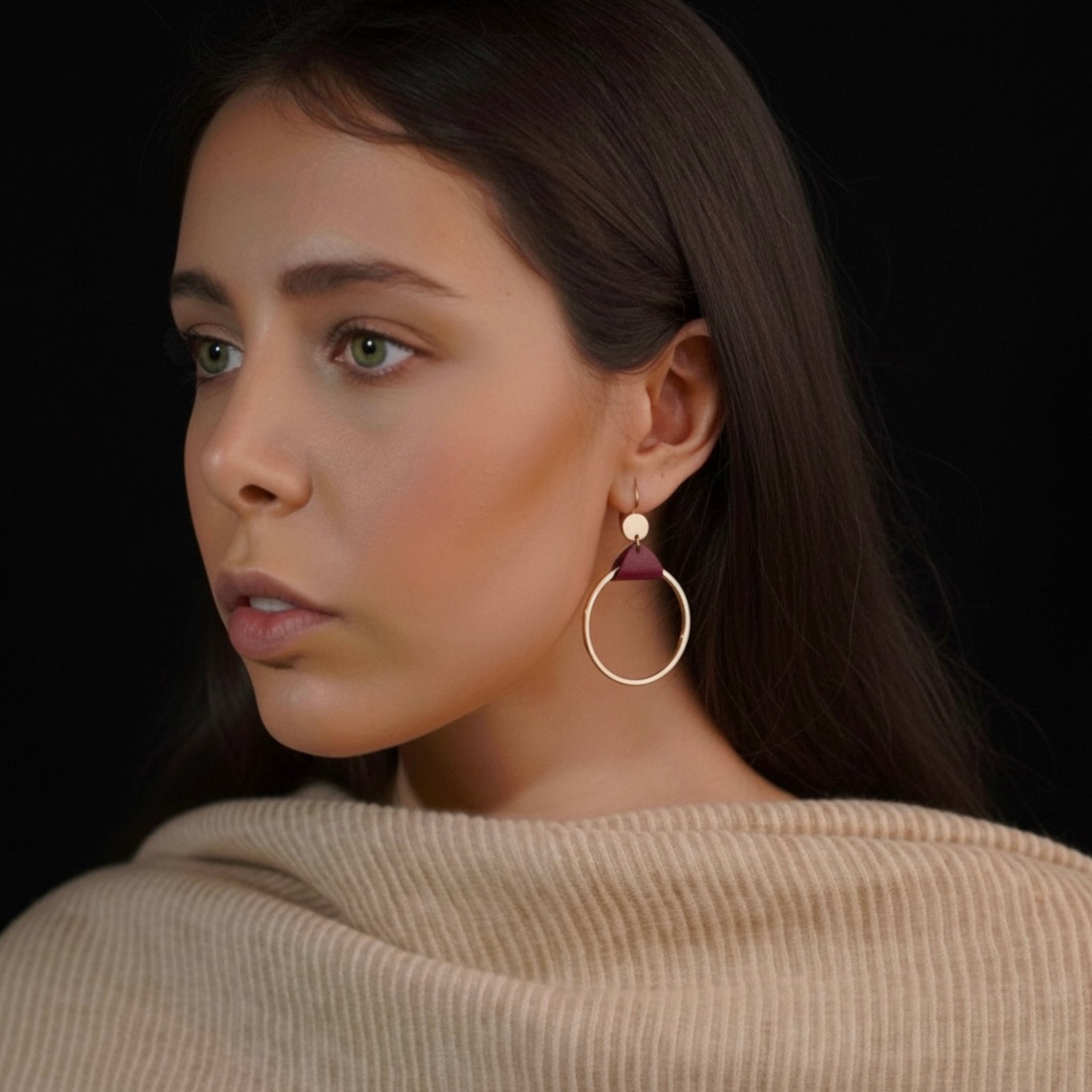 Femme brune portant les Boucles d'oreilles dorées Cléa, grands anneaux créoles, noués par un morceau de cuir pourpre aux accroches dormeuses