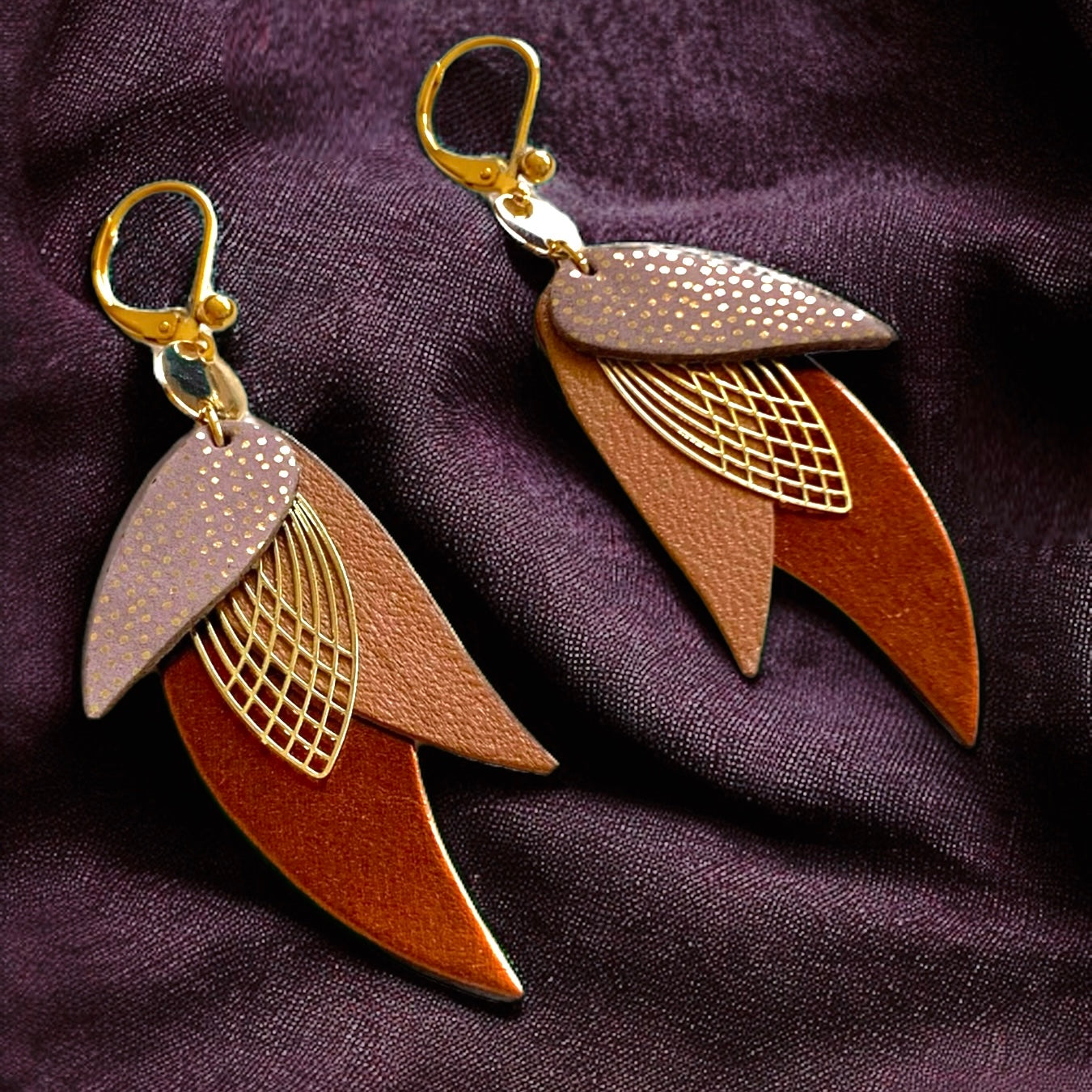 boucles d'oreilles dorées Nune modèle Ara en plumes de cuirs rose Mountbatten pailleté or, camel et chocolat métallisé, sur fond prune