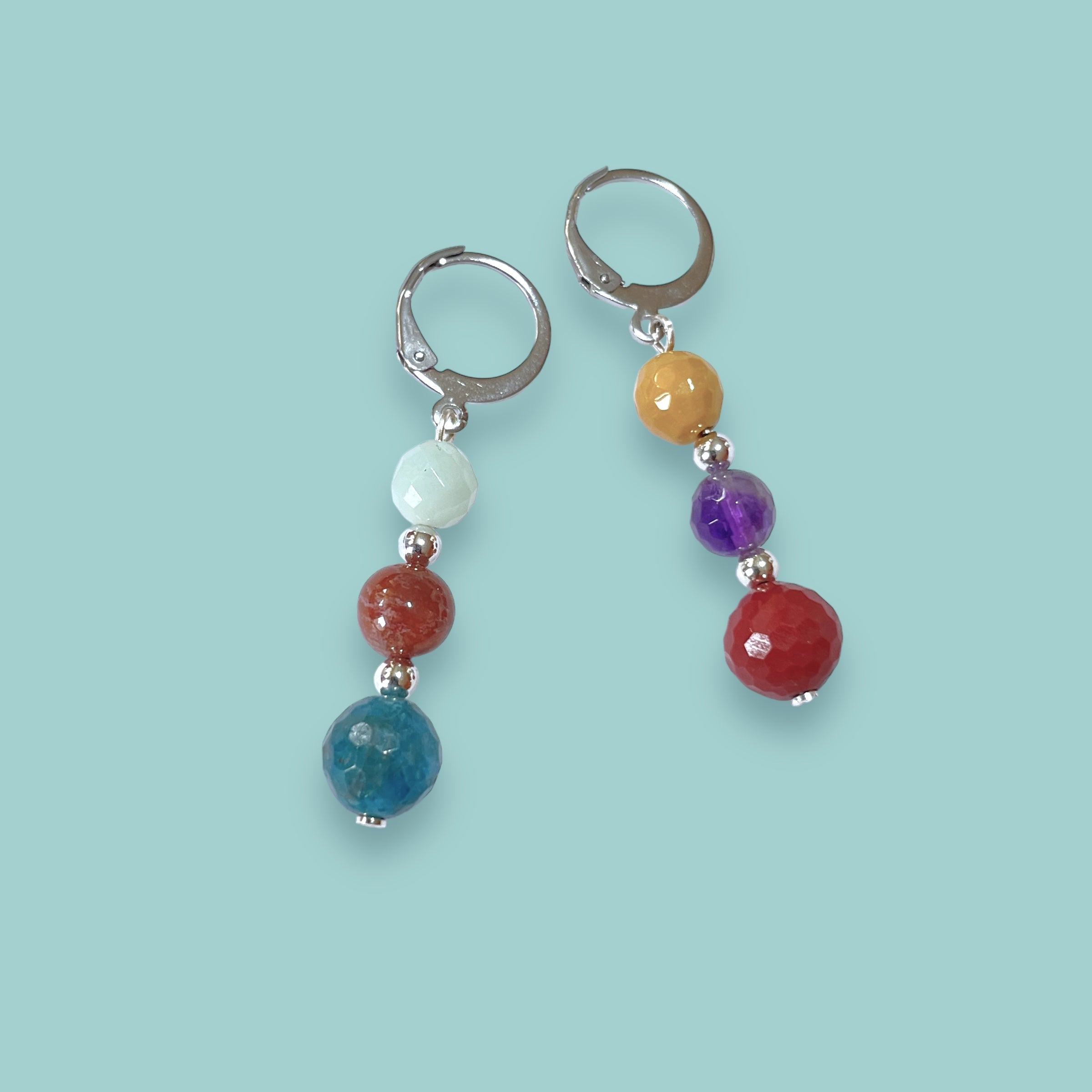 2 boucles d'oreilles pendantes argentées en perles de pierres naturelles colorées sur fond vert pastel