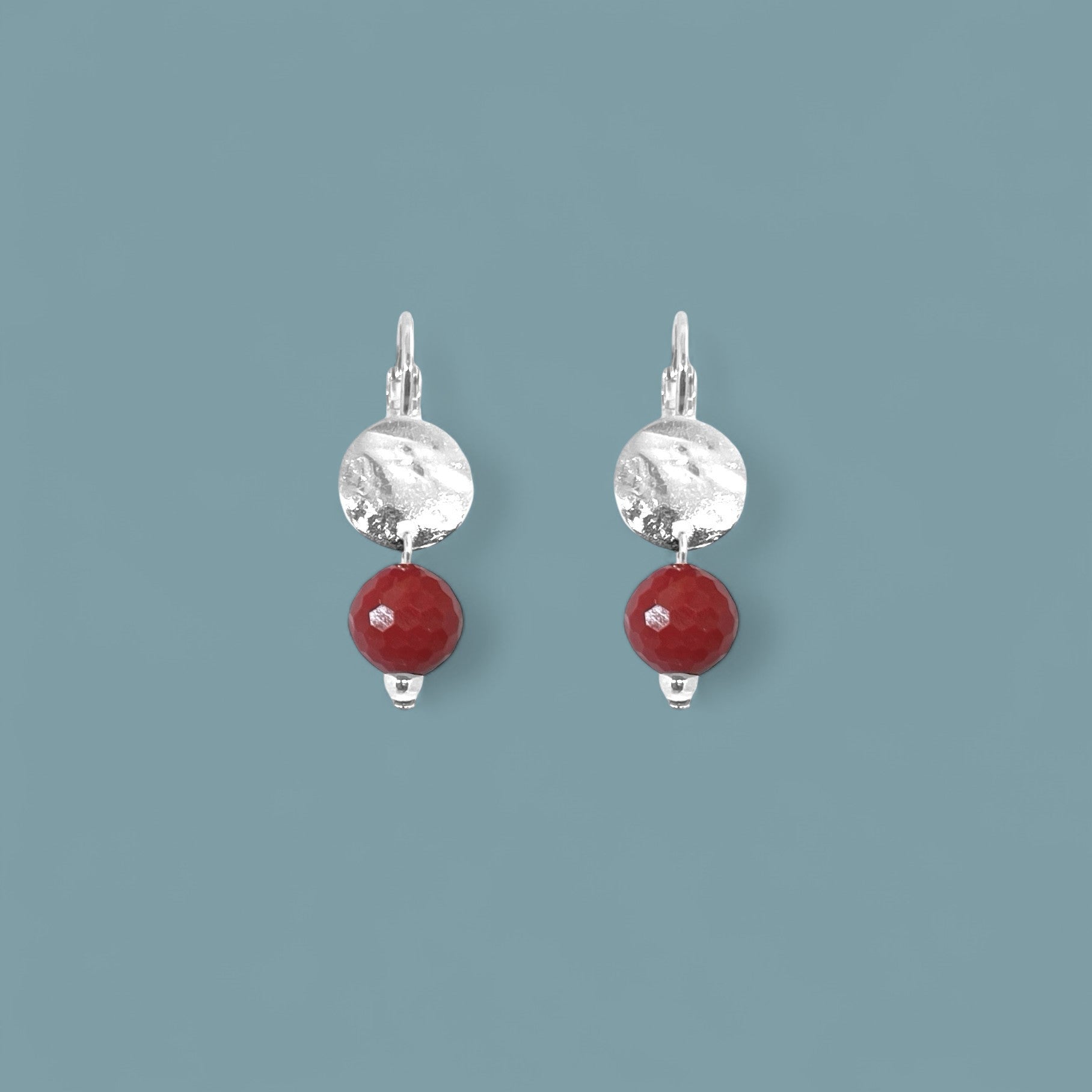 Petites boucles d'oreilles rondes en métal martelé doré à l'or fin avec pendant en perle de mokaïte bordeaux, sur fond bleu gris
