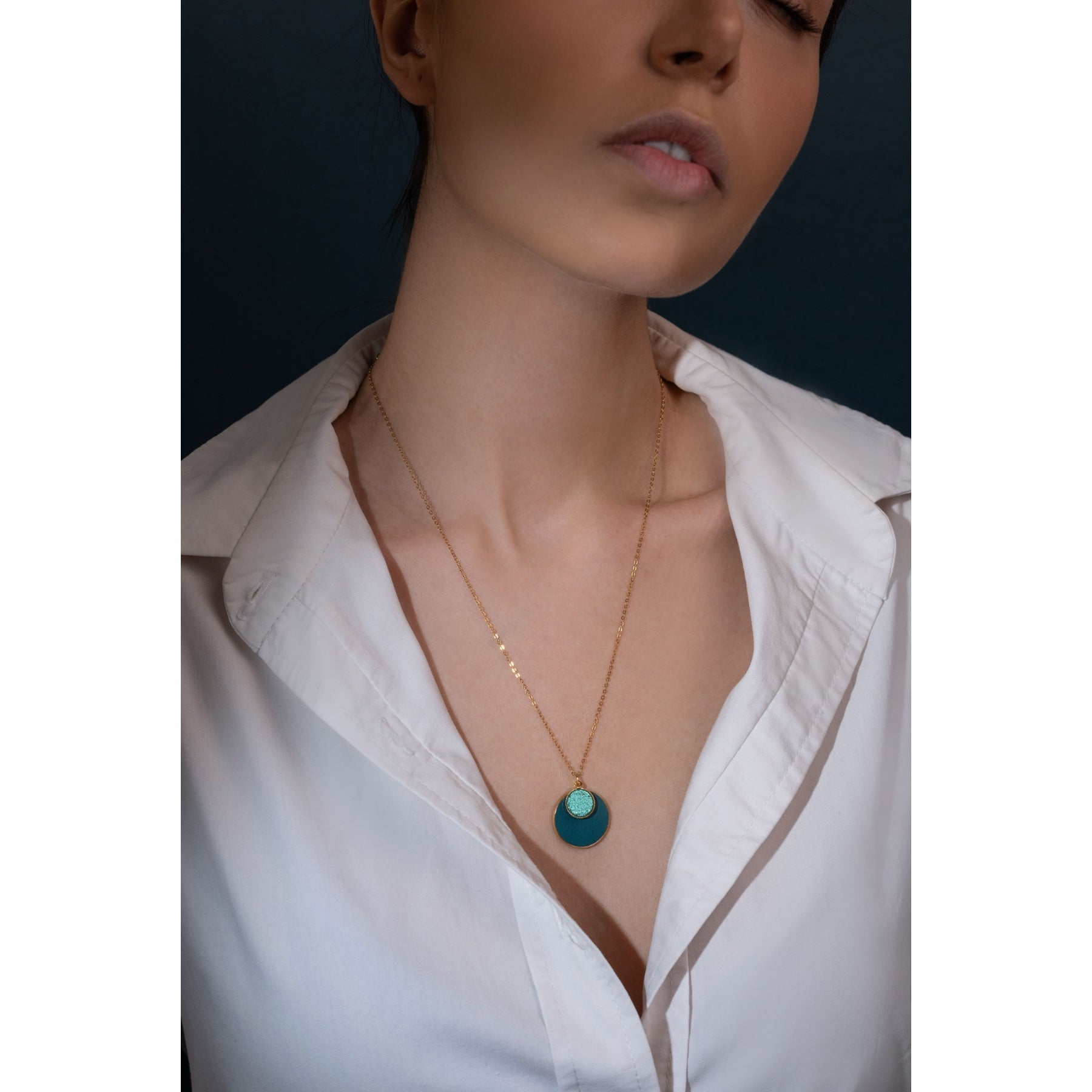 Collier Bulle Nune, court doré avec pendentif rond composé de doubles sertis de cuirs vert canard et vert émeraude brillant intense, porté par une femme brune