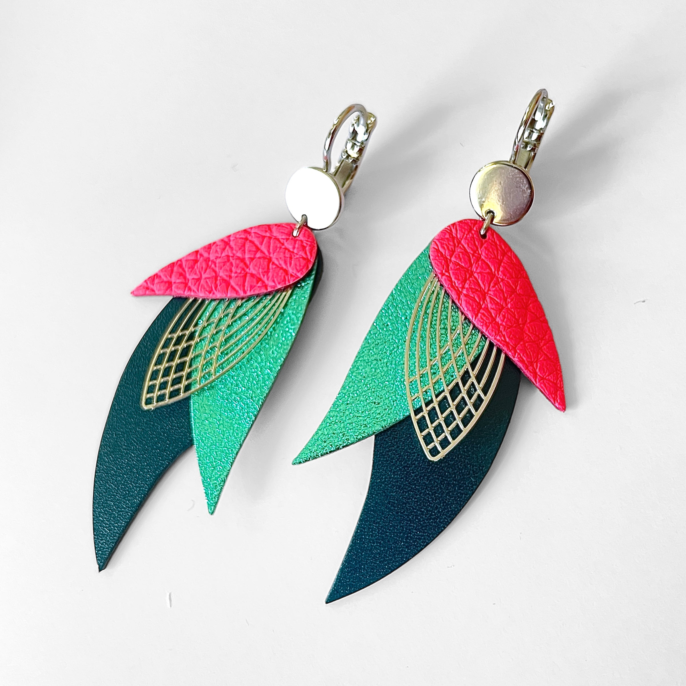 Boucles d'oreilles argentées Nune en forme de plumes, modèle Ara en cuirs rose fluo grainé, turquoise métallisé et vert canard sur fond blanc