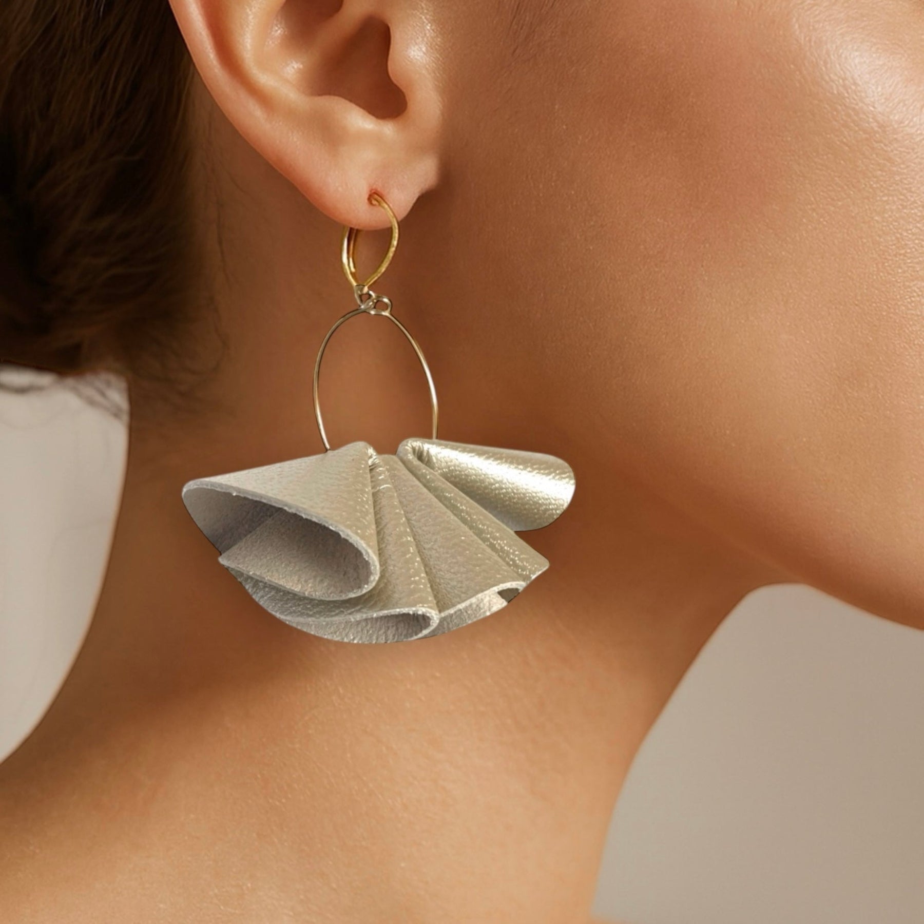 Grandes boucles d'oreilles dorées aériennes et sculpturales en cuir plissé doré clair perlé,, portées à l'oreille