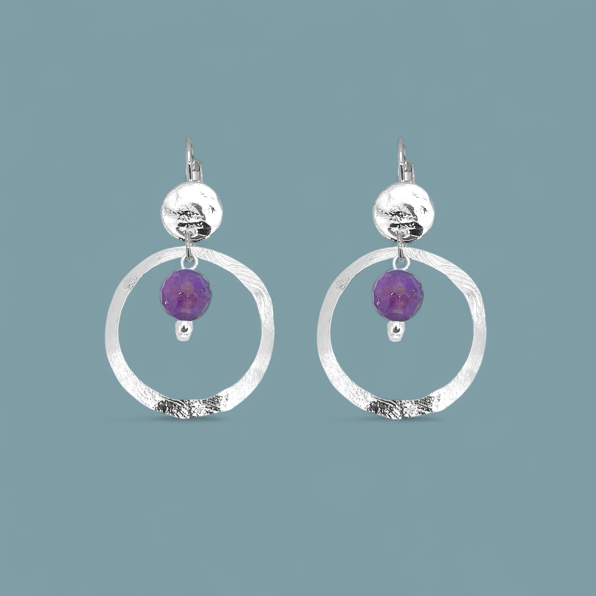 Petites boucles d'oreilles créoles argentées pendantes rondes avec perles d'améthyste, sur fond bleu gris