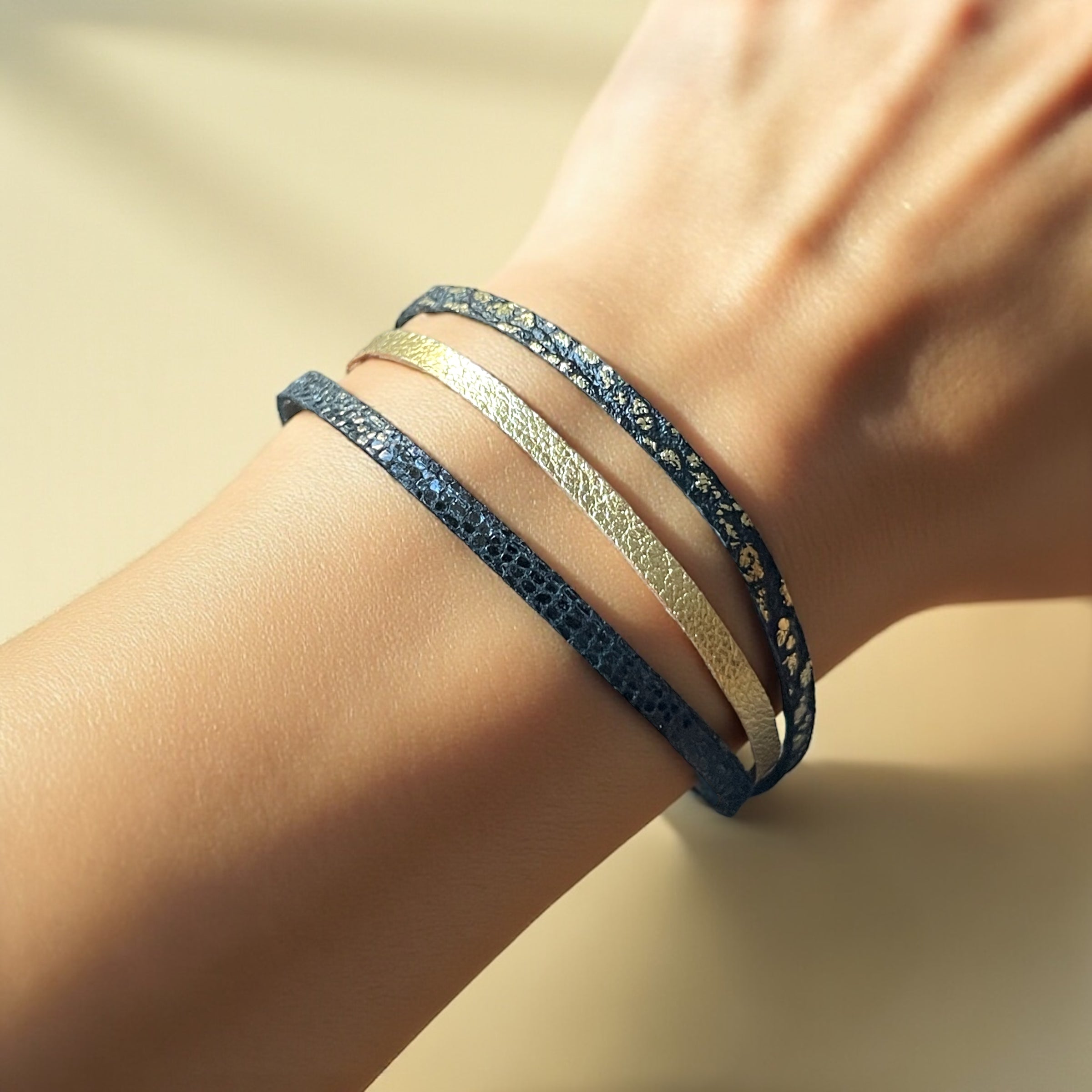 Cielo Bracelet femme tricolore à 3 liens avec fermoir aimanté doré, en cuirs doré, noir grainé or et noir brillant façon serpent, porté au poignet, sur fond clair