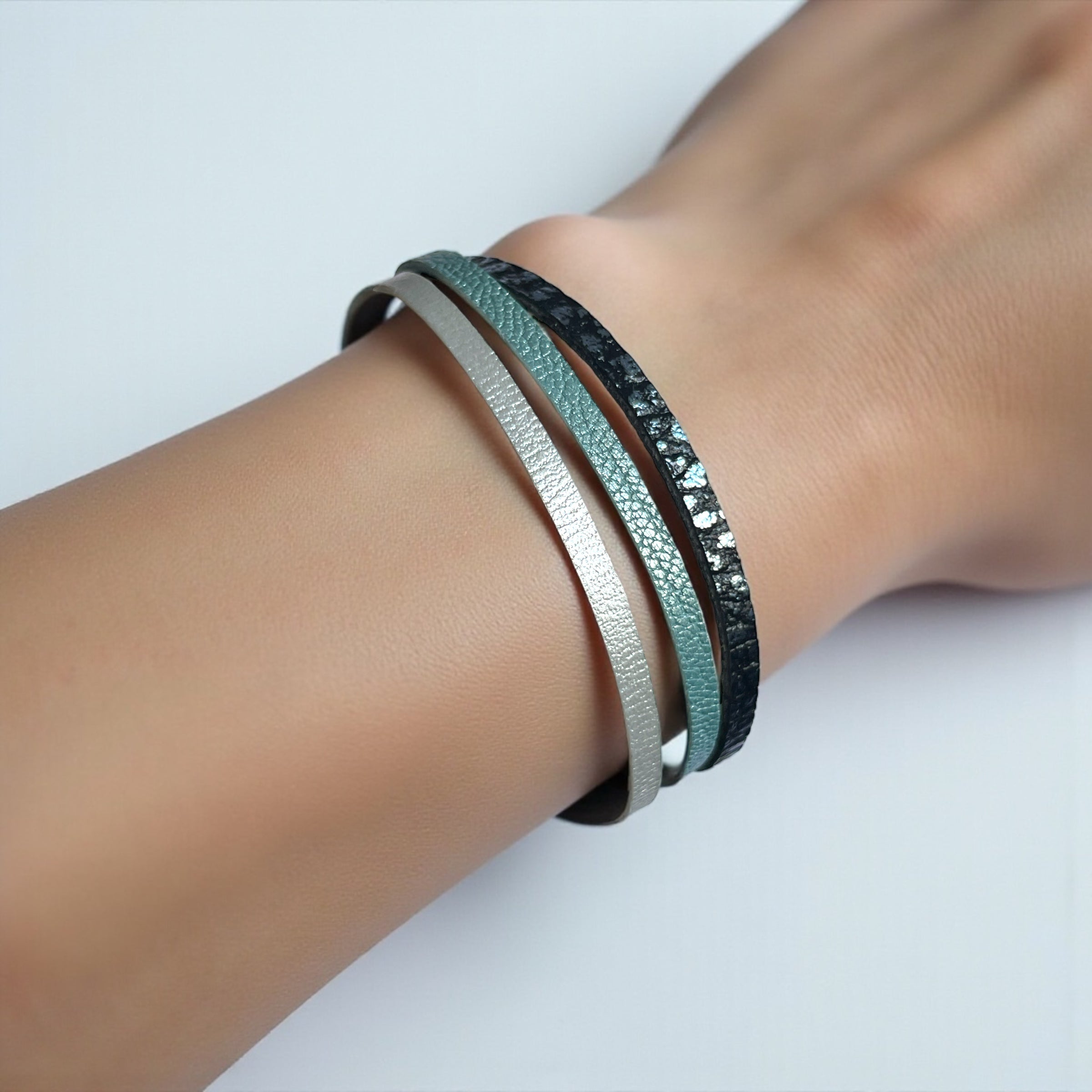 Cielo Bracelet femme tricolore à 3 liens avec fermoir aimanté doré, en cuirs bleu gris nacré, bleu glacier métallisé grainé, et champagne nacré, porté au poignet, sur fond blanc