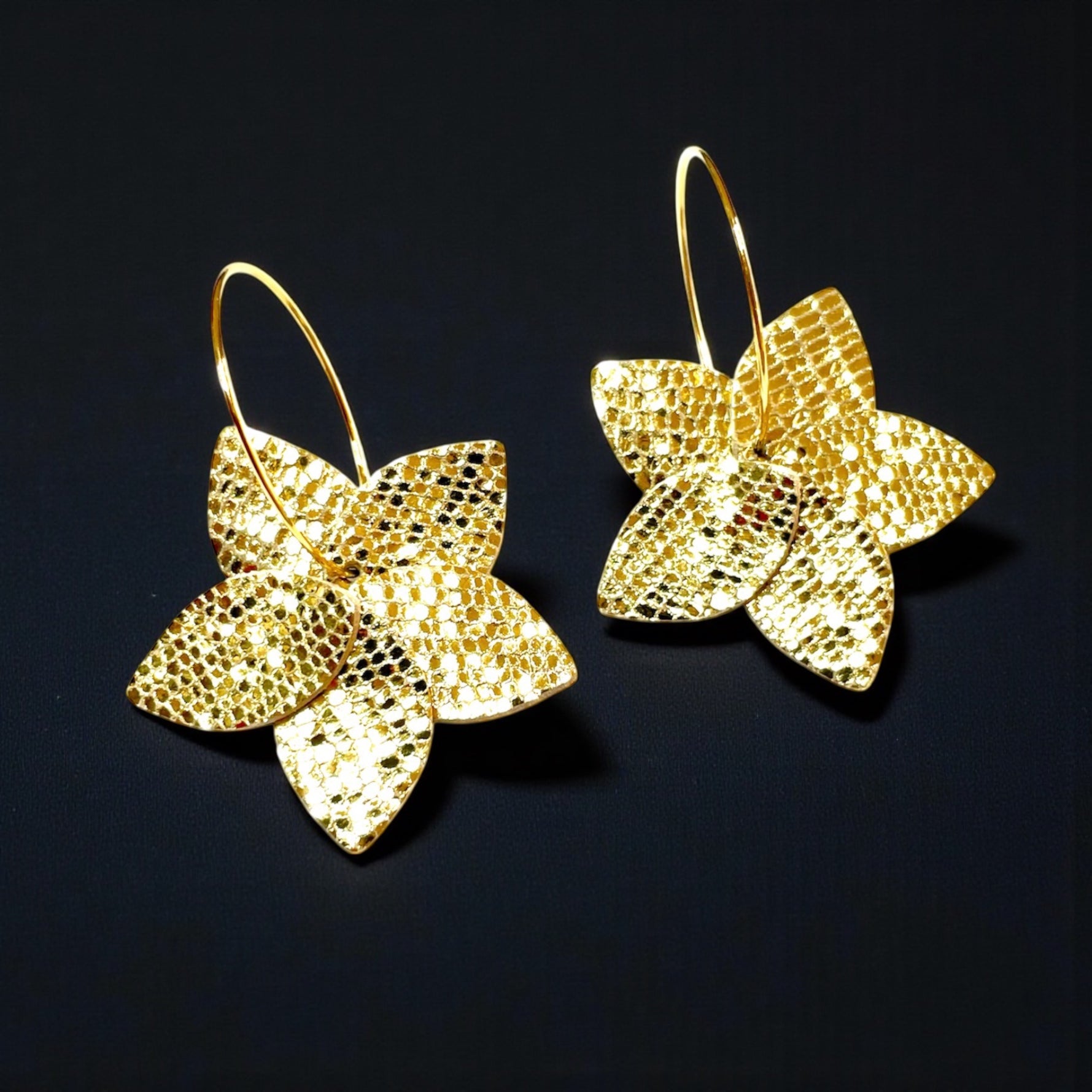 Nune petites boucles d'oreilles créoles Jasmin en cuir doré façon serpent recyclé et anneaux dorés, vues de dessus, sur fond noir