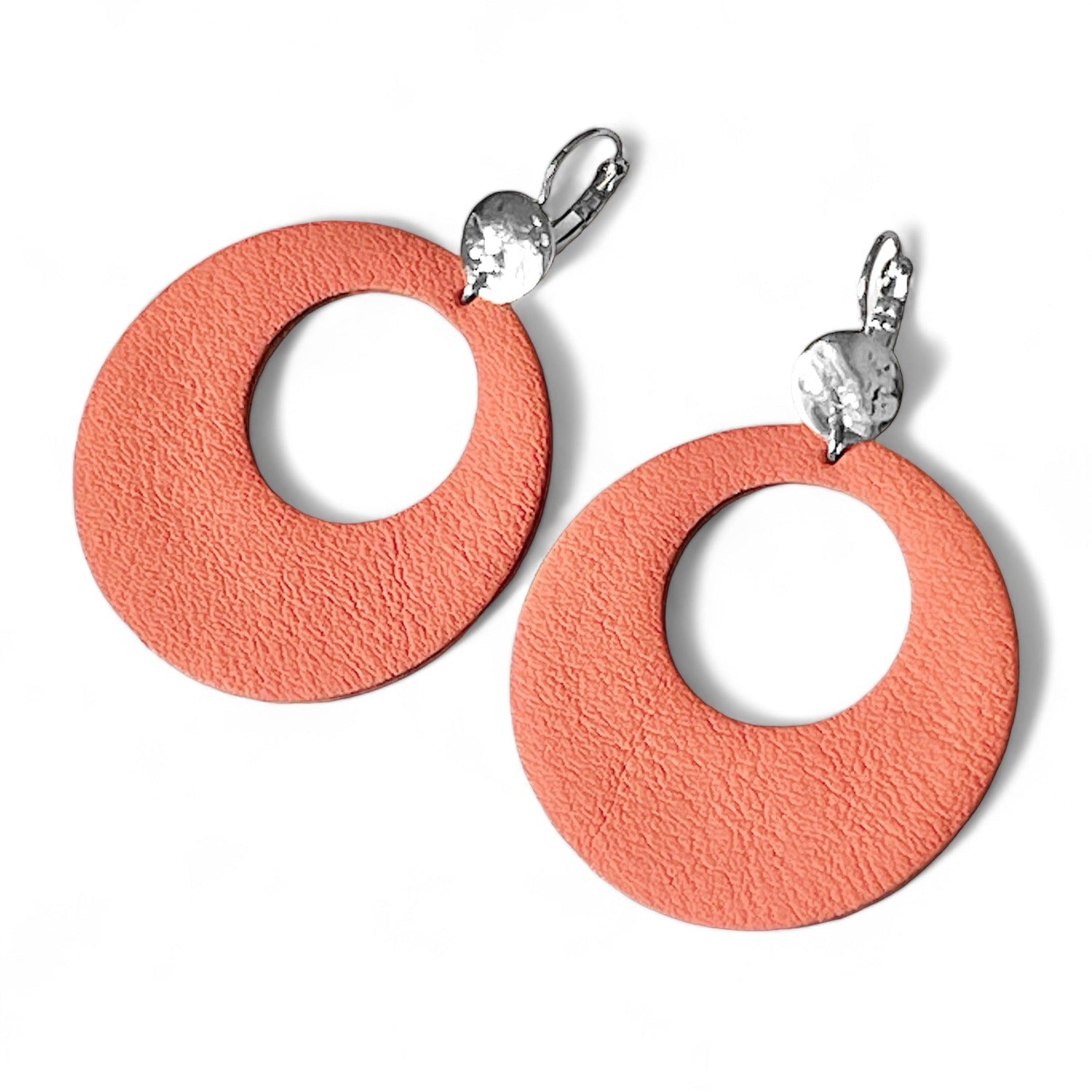 Boucles d'oreilles argentées, grandes créoles rondes en cuir saumon clair au style vintage, sur fond blanc