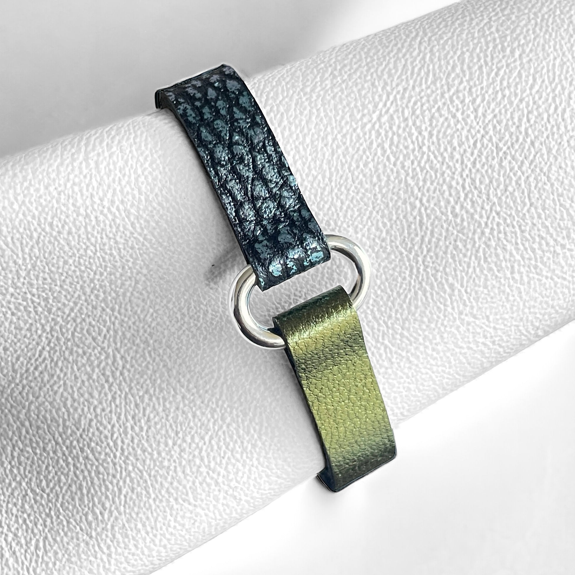 Bracelet bicolore à boucle argent en cuirs recyclés bleu glacier métallisé grainé et kaki métallisé, enroulé autour d'un rouleau de cuir blanc