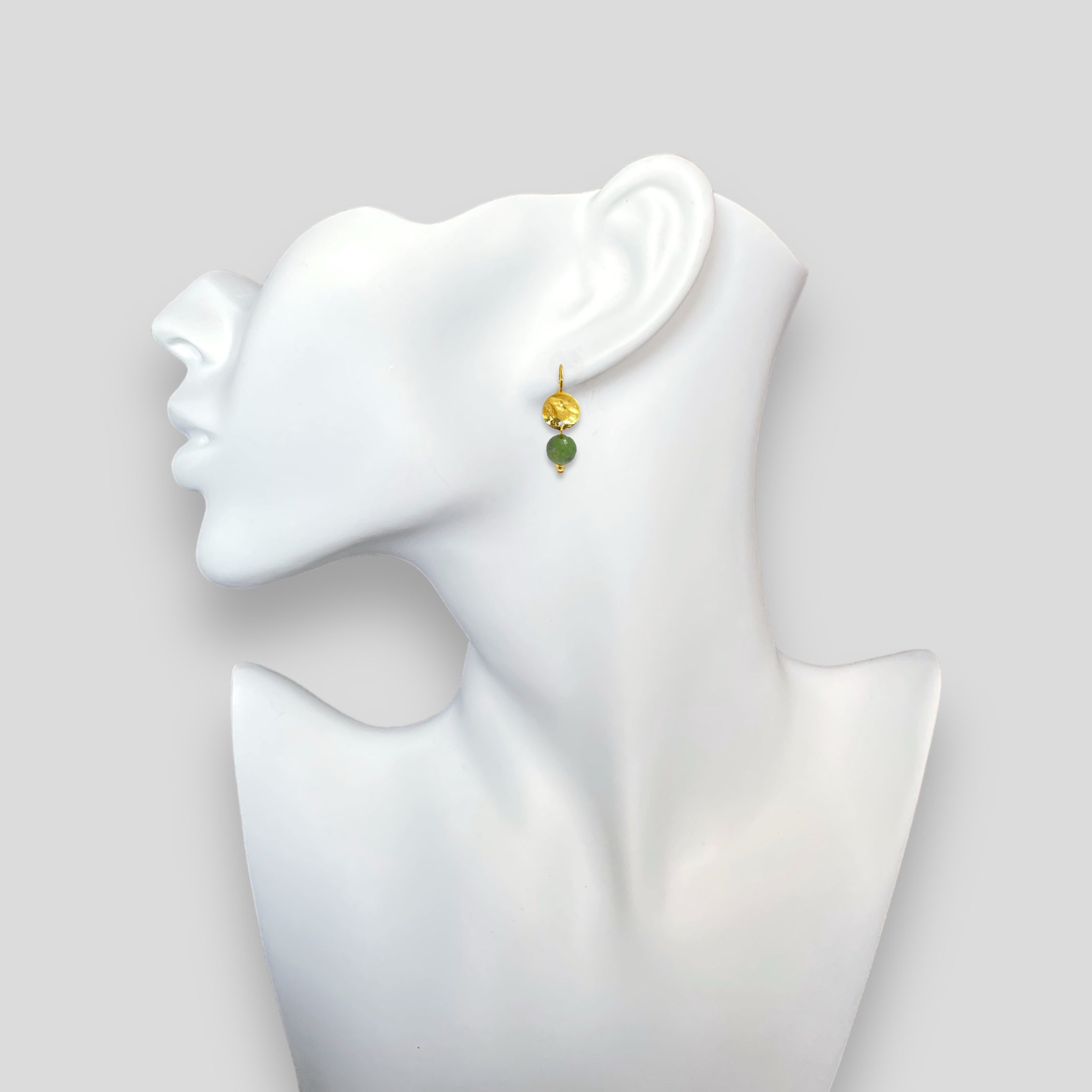 Petites boucles d'oreilles rondes en métal martelé doré à l'or fin avec pendant en perle d'opale verte, portées à l'oreilles sur un buste blanc