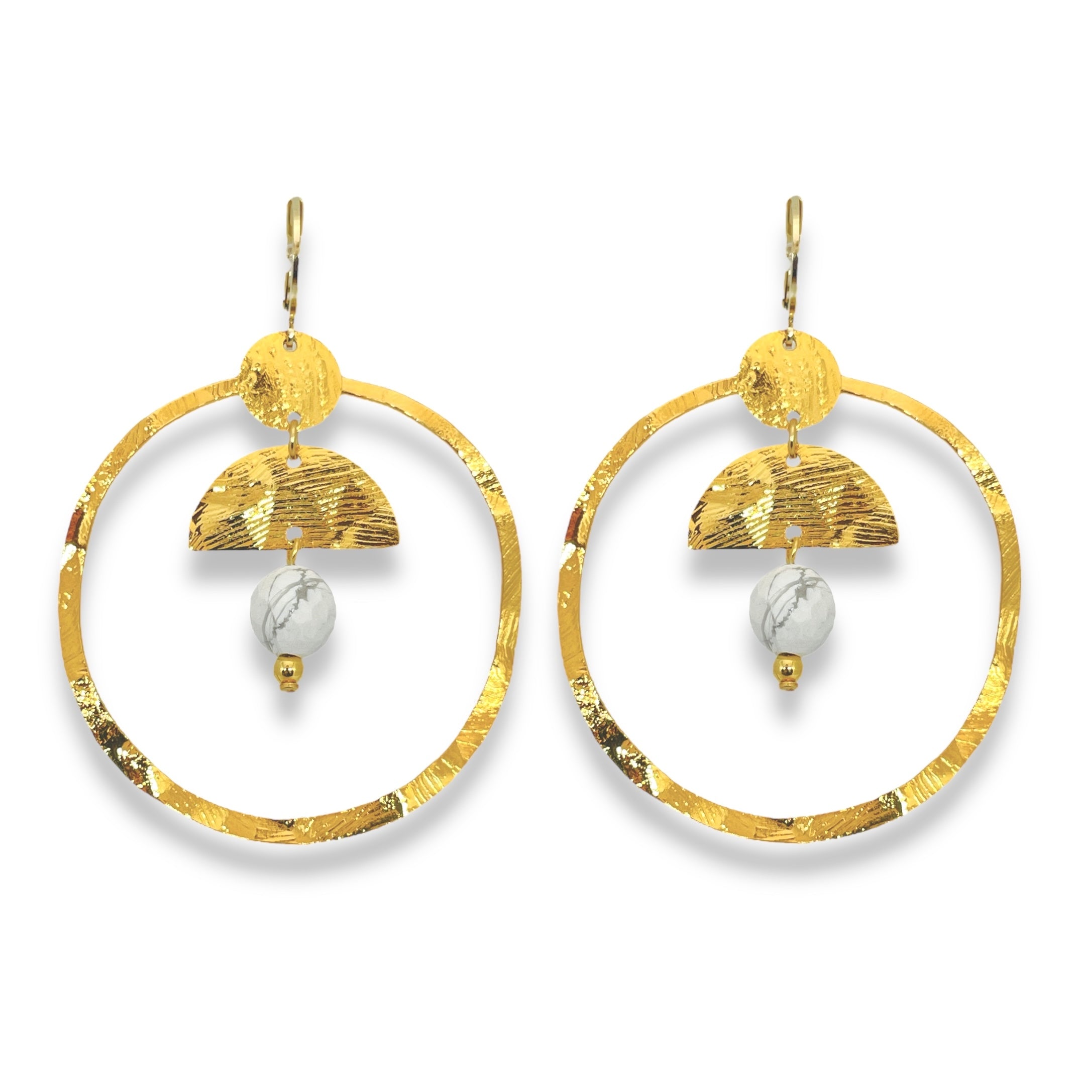 Grandes boucles d'oreilles créoles en métal martelé doré à l'or fin et pierres naturelles howlite blanche accrochée à une demi-lune, sur fond blanc
