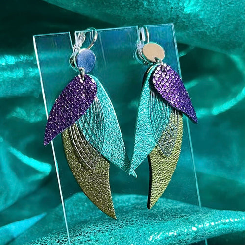Boucles d'oreilles argentées Nune en forme de plumes, modèle Ara en cuirs violet brillant façon serpent, turquoise métallisé et kaki métallisé sur fond cuir turquoise métallisé