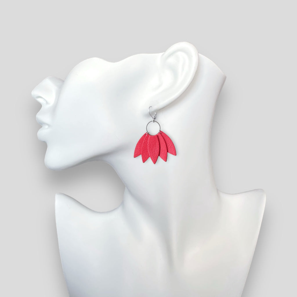 Grandes boucles d'oreilles argentées n forme de couronne de plumes en cuir rose saumon, portées à l'oreille sur un buste blanc