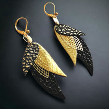 Charger l'image dans la galerie, boucles d'oreilles dorées Nune modèle Ara en plumes de cuirs noir brillant façon serpent, doré brillant et noir grainé or, sur fond noir
