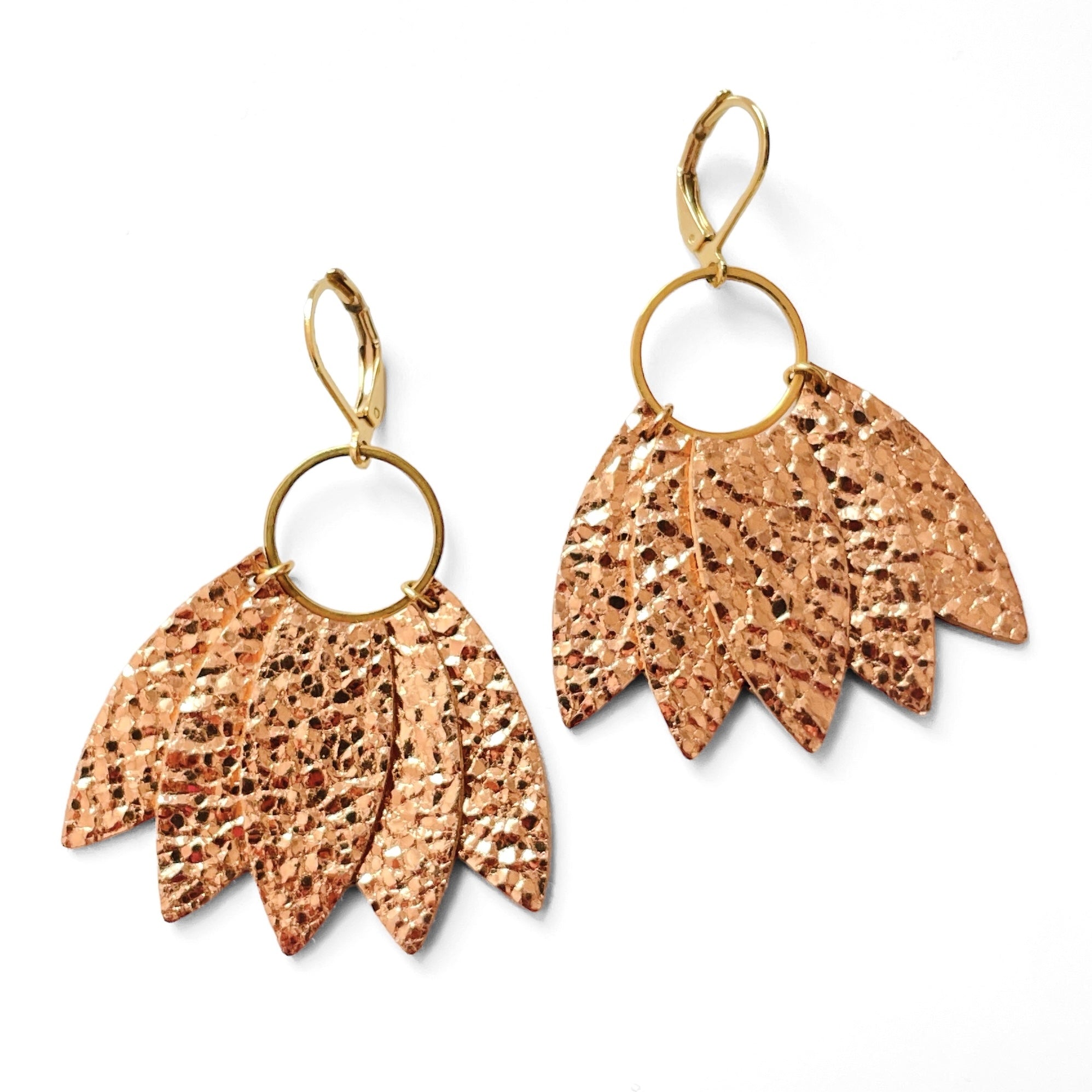 Grandes boucles d'oreilles dorées en forme de couronne de plumes en cuir or rosé froissé, sur fond blanc