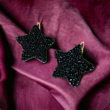 Charger l&#39;image dans la galerie, Boucles d&#39;oreilles Diva en forme d&#39;étoile en cuir recyclé noir grainé pailleté, sur fond velours mauve
